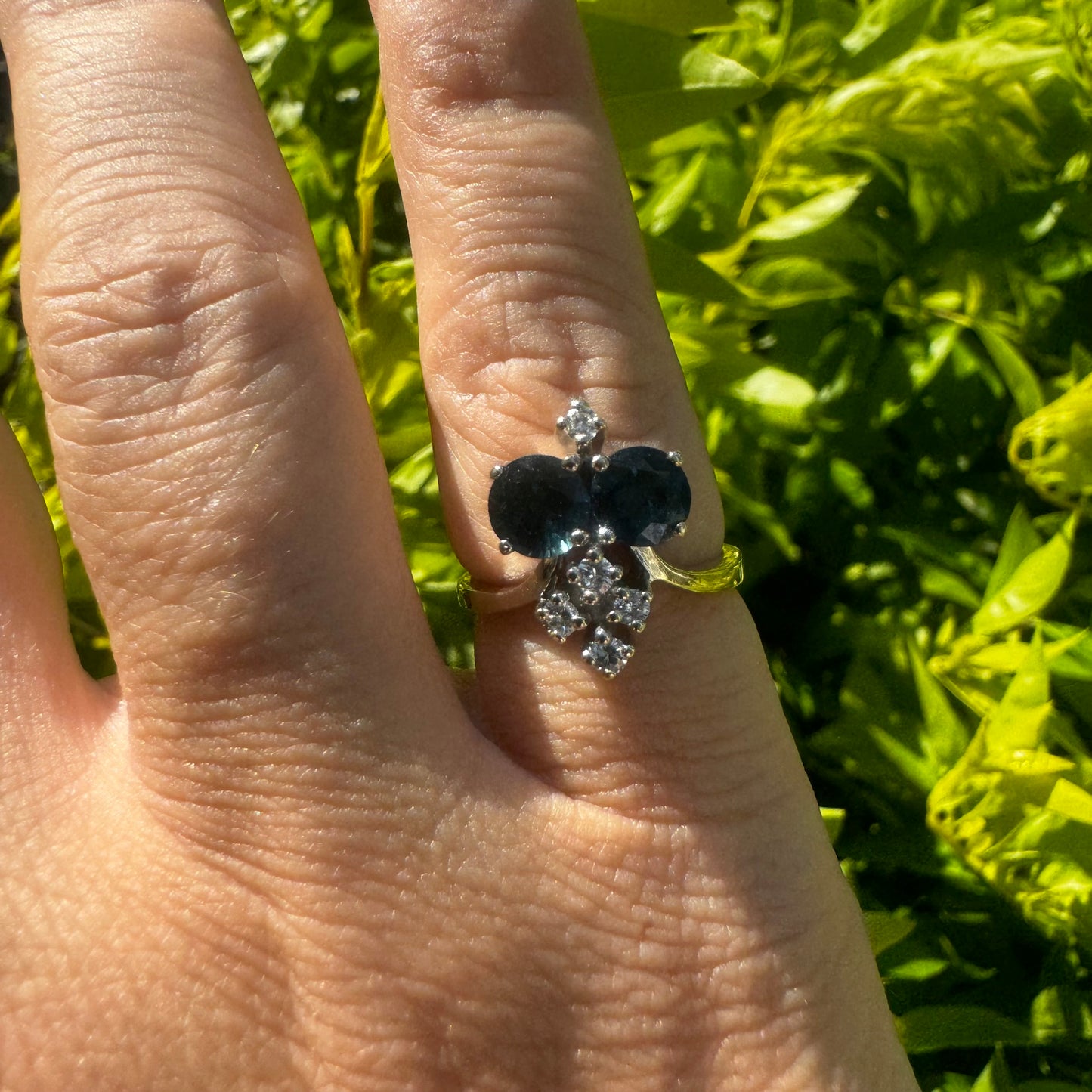 14K gold ring set with two deep blue oval Sapphires accented by clusters of brilliant white Diamonds.