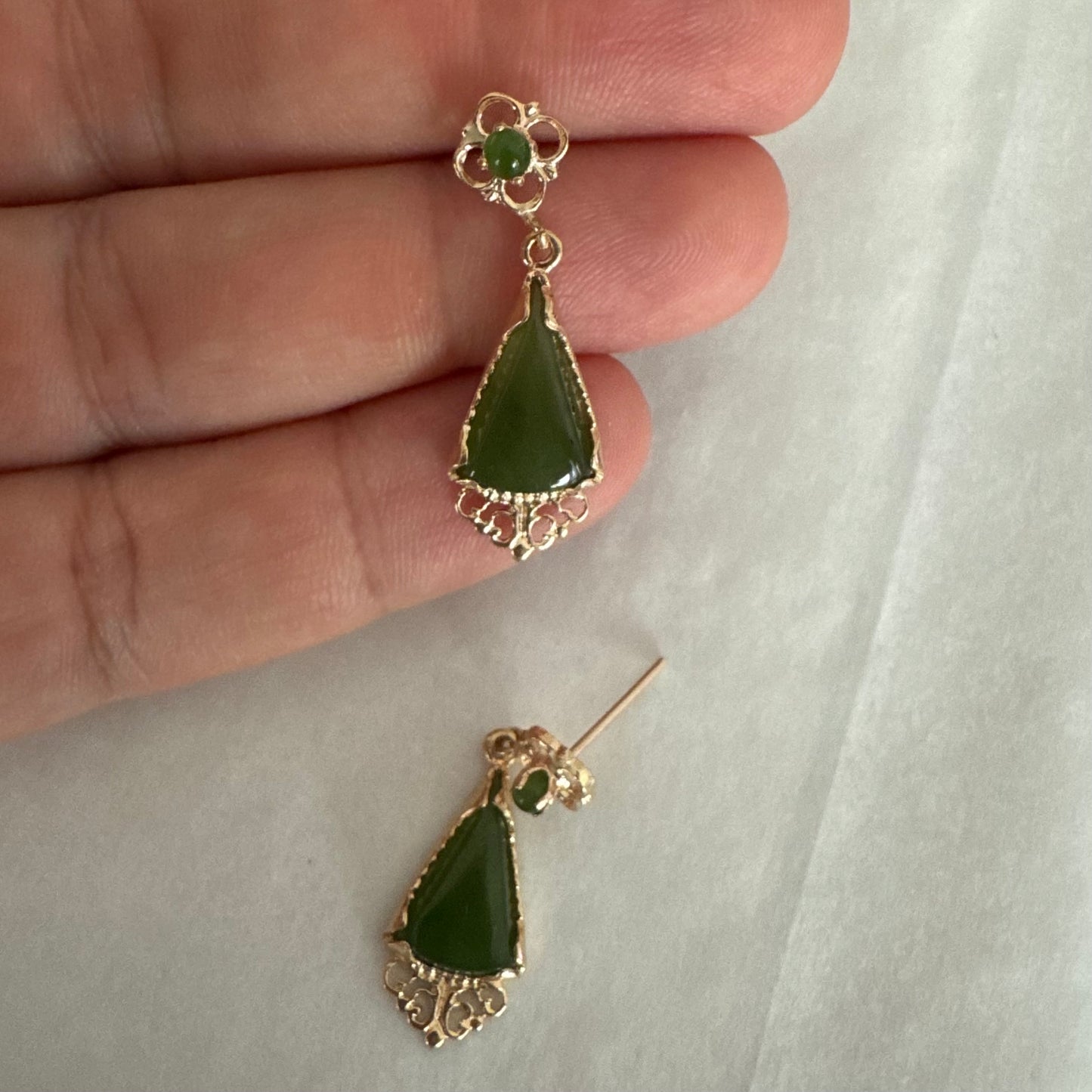 עגילי זהב צהוב 14 קראט משובצים אבני ג׳ייד ירוקות בגוון עמוק בחיתוך משולש.