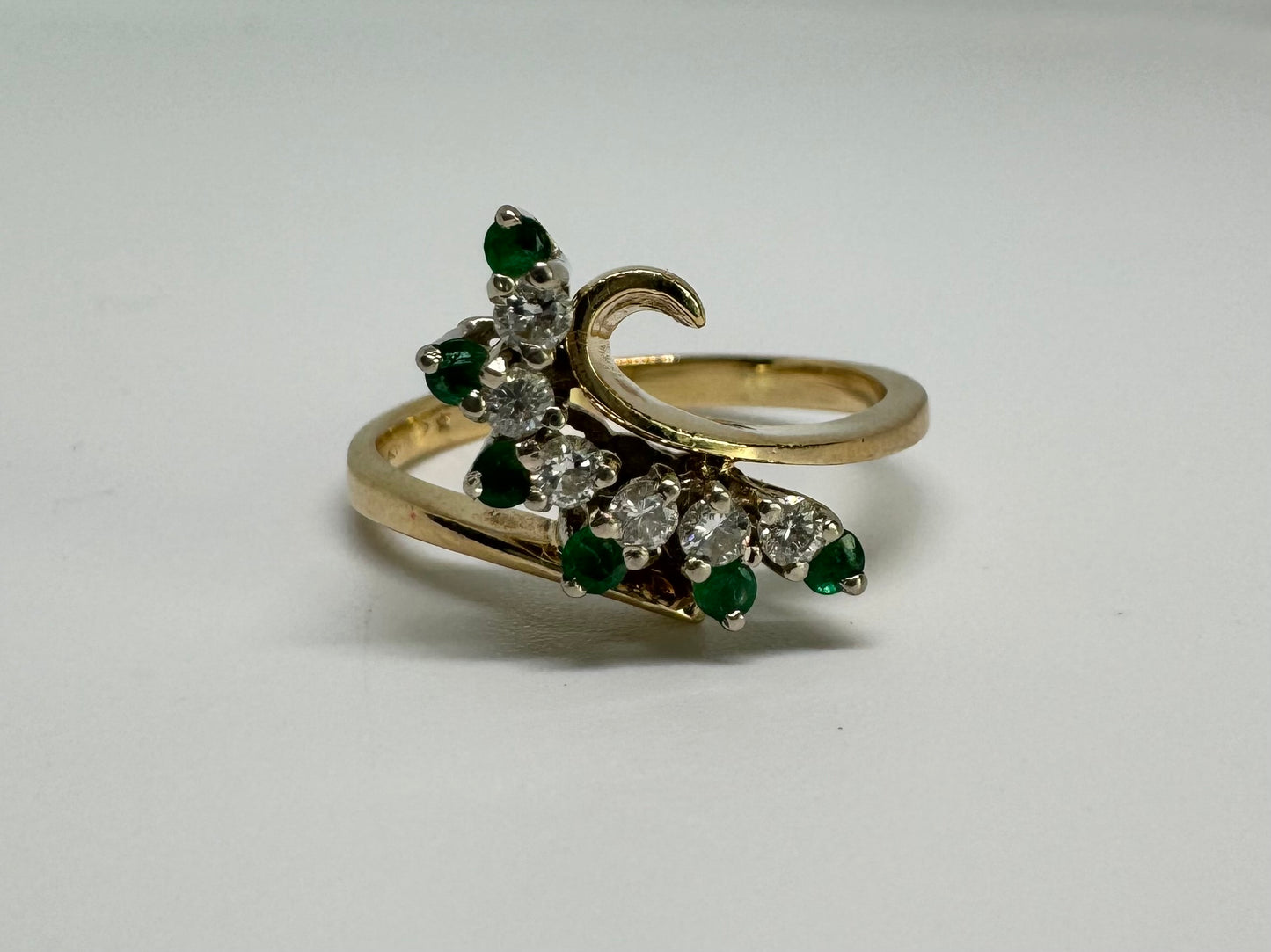 14K gold open ring featuring a delicate swirl set with Emeralds and brilliant-cut Diamonds
