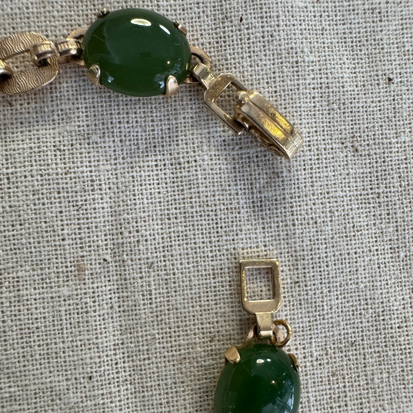 צמיד זהב צהוב 14 קראט משובץ באבני ג’ייד ירוקות בחיתוך קבושון (cabochon) בעיצוב אליפטי, המחוברות ביניהן בחוליות זהב עם טקסטורה מעניינת.