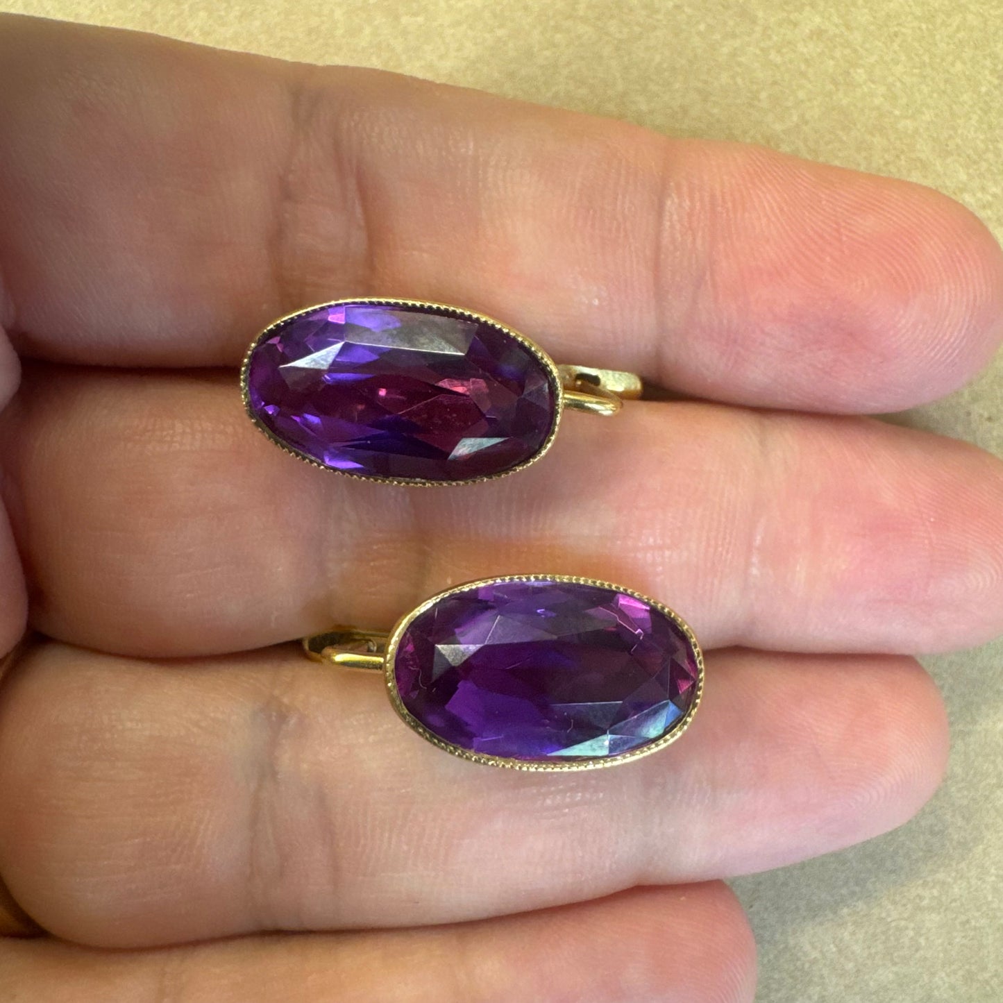 עגילי זהב צהוב 18 קראט, תלויים קצרים, משובצים באבני אמטיסט סגולות בחיתוך אובלי עמוק.
