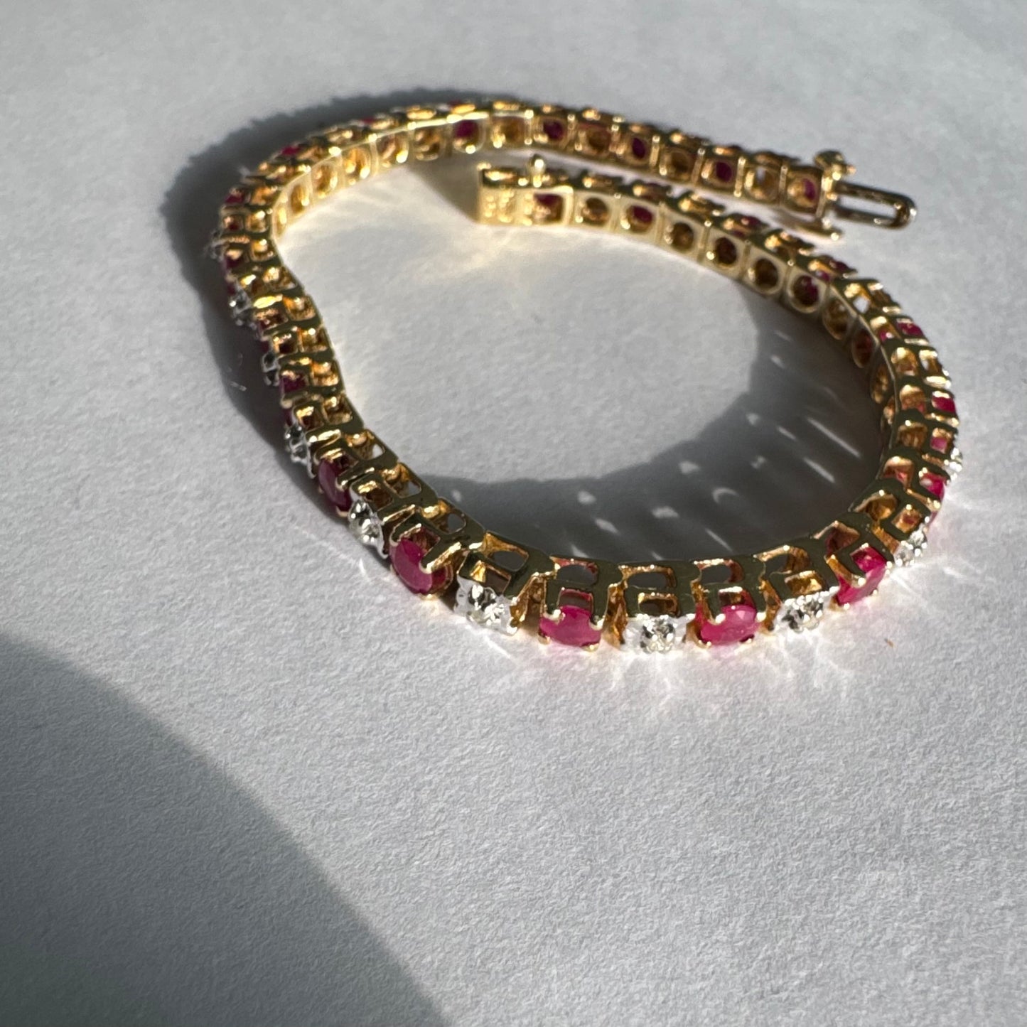 צמיד זהב צהוב 10 קראט משובץ אבני רובי בגוון אדום עמוק וביניהן יהלומים לבנים מנצנצים.