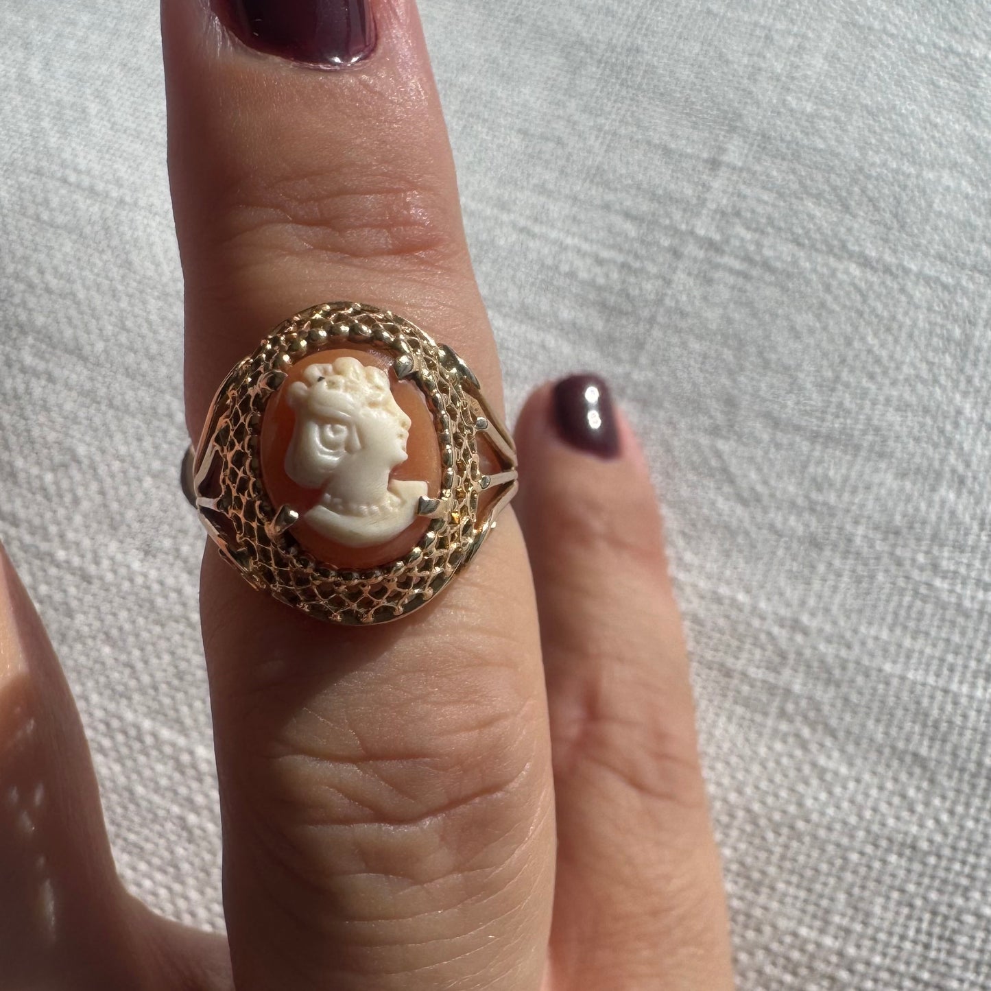 18K gold ring featuring a hand-carved Cameo of a delicate female profile in ivory tones on a warm Coral background.