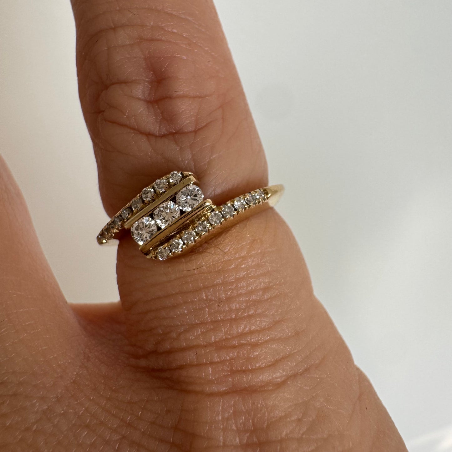 טבעת זהב צהוב 14 קראט בעיצוב ייחודי, משובצת שלושה יהלומים מרכזיים ושורות נוספות של יהלומים לאורך הזרועות. 