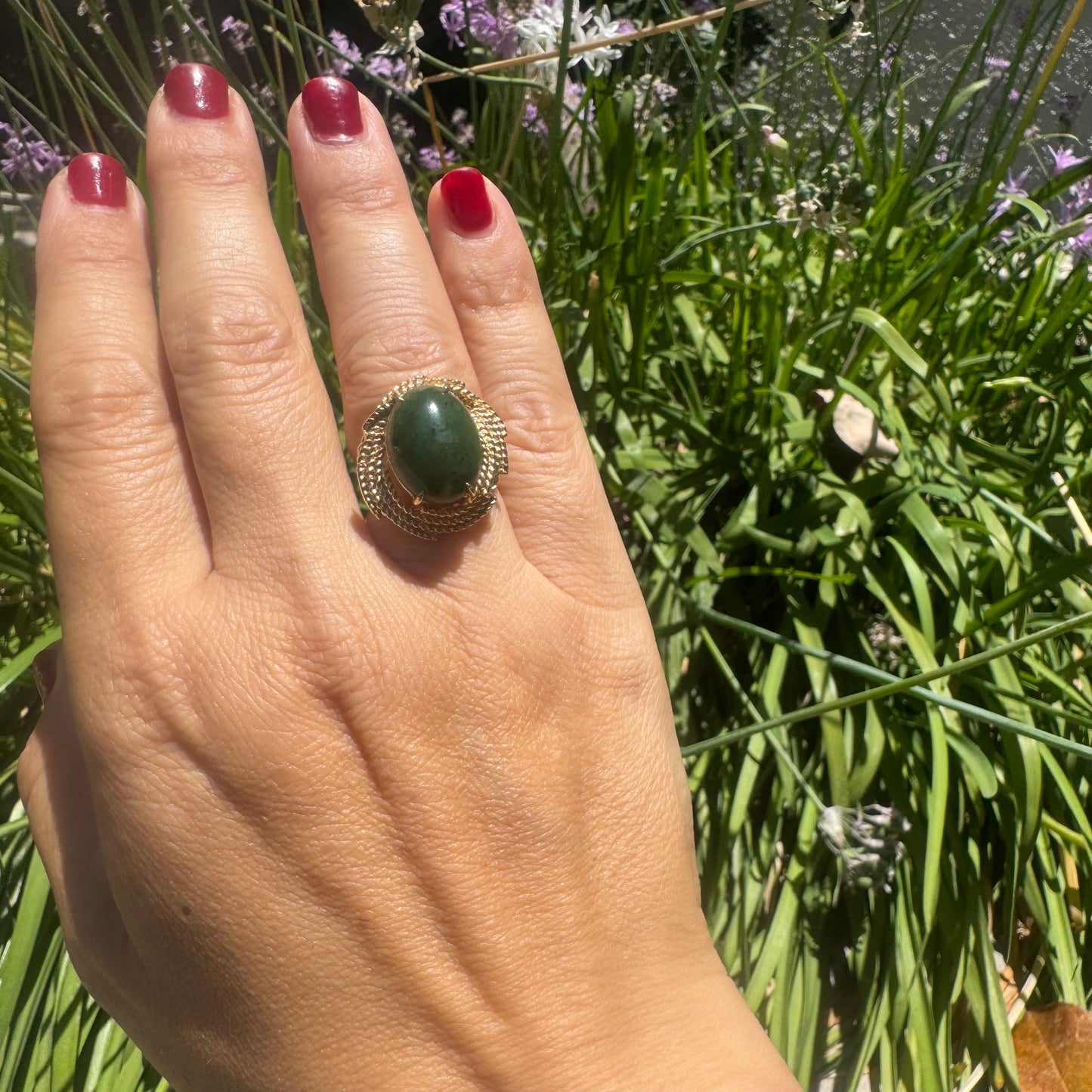 14K gold ring set with a deep green Jade set in a textured gold frame.