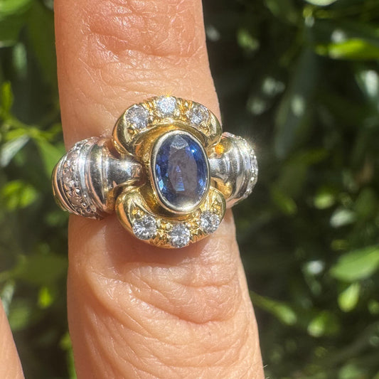 טבעת זהב לבן וצהוב 18 קראט, משובצת עם אבן טנזנייט ומוקפת ביהלומים עגולים נוצצים.