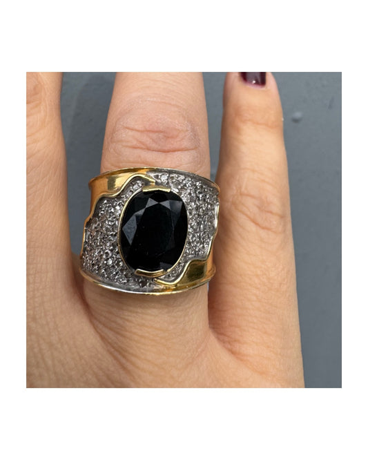 טבעת זהב צהוב 18 קראט משובצת יהלומים ואבן ספיר בצבע כחול כהה במרכז בעלת עיצוב דרמטי ואלגנטי בסגנון וינטג׳-יוקרתי