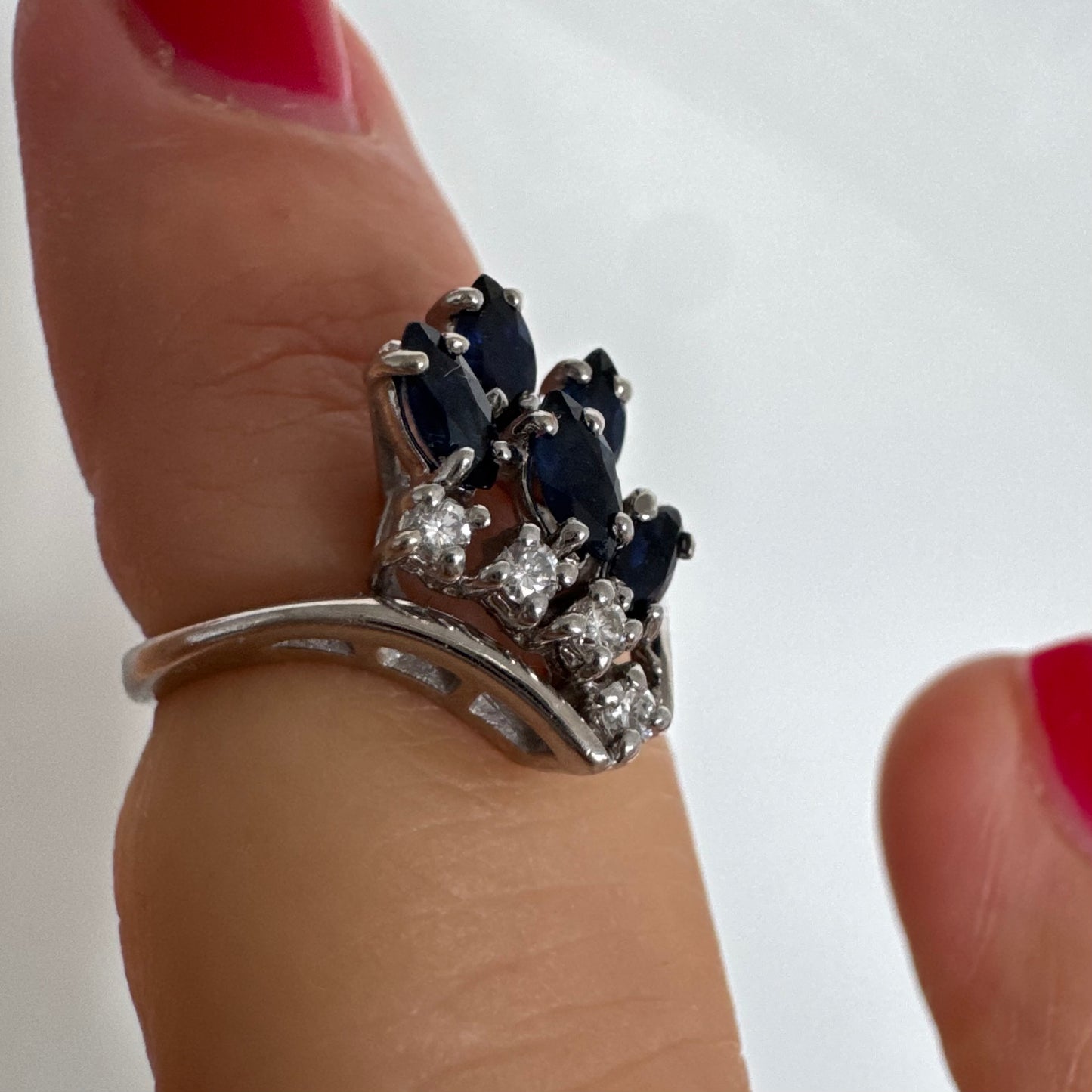 טבעת זהב לבן 14 קראט משובצת אבני ספיר כחולות בחיתוך מרקיזה ויהלומים, היוצרים מראה אלגנטי ודינמי.