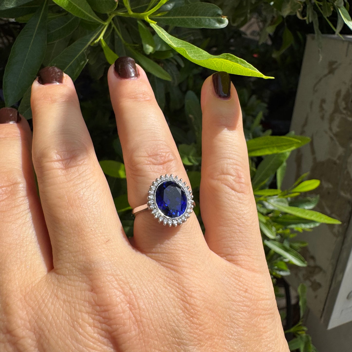14K gold ring set with a deep blue oval Sapphire surrounded by a halo of sparkling Diamonds
