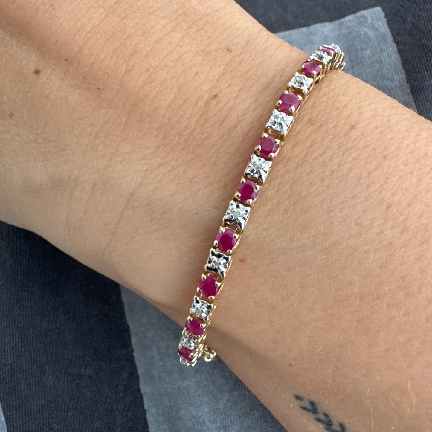 צמיד זהב צהוב 10 קראט משובץ אבני רובי בגוון אדום עמוק וביניהן יהלומים לבנים מנצנצים.