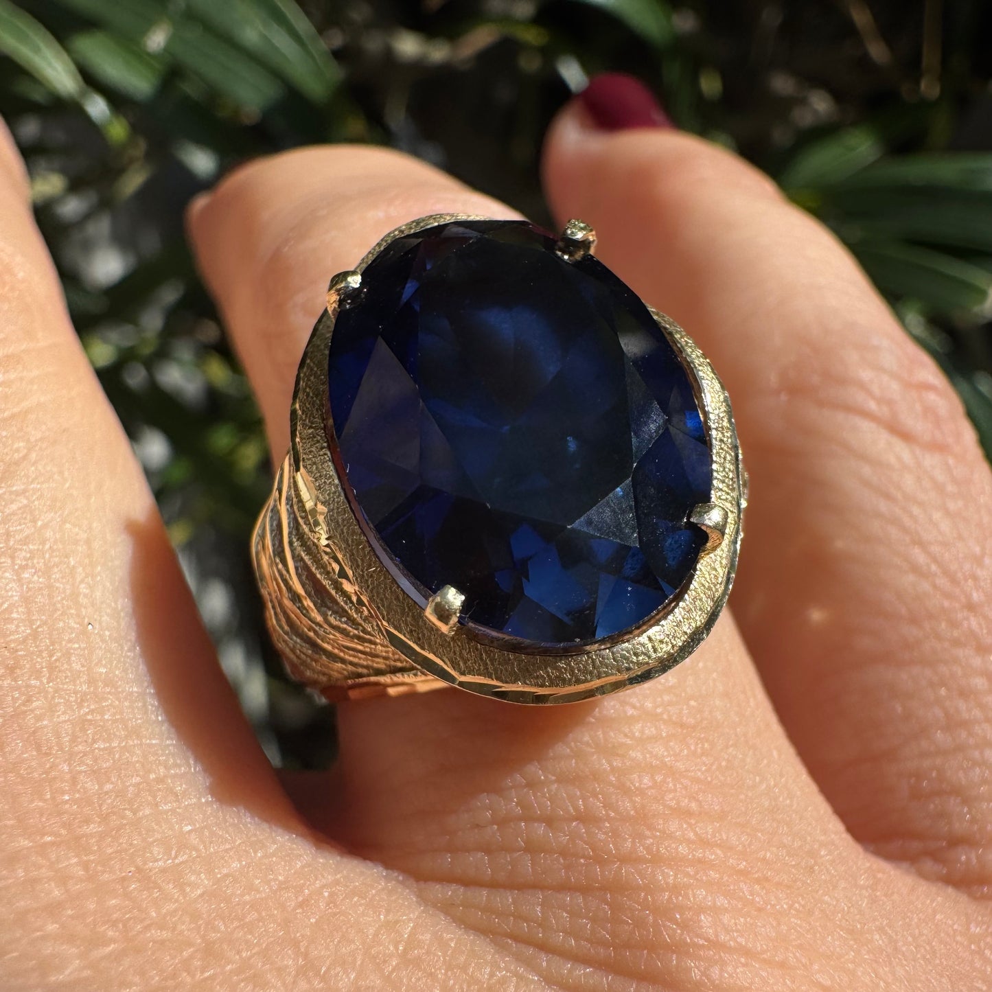 14K gold ring set with a deep navy-blue oval Sapphire in a dramatic openwork setting