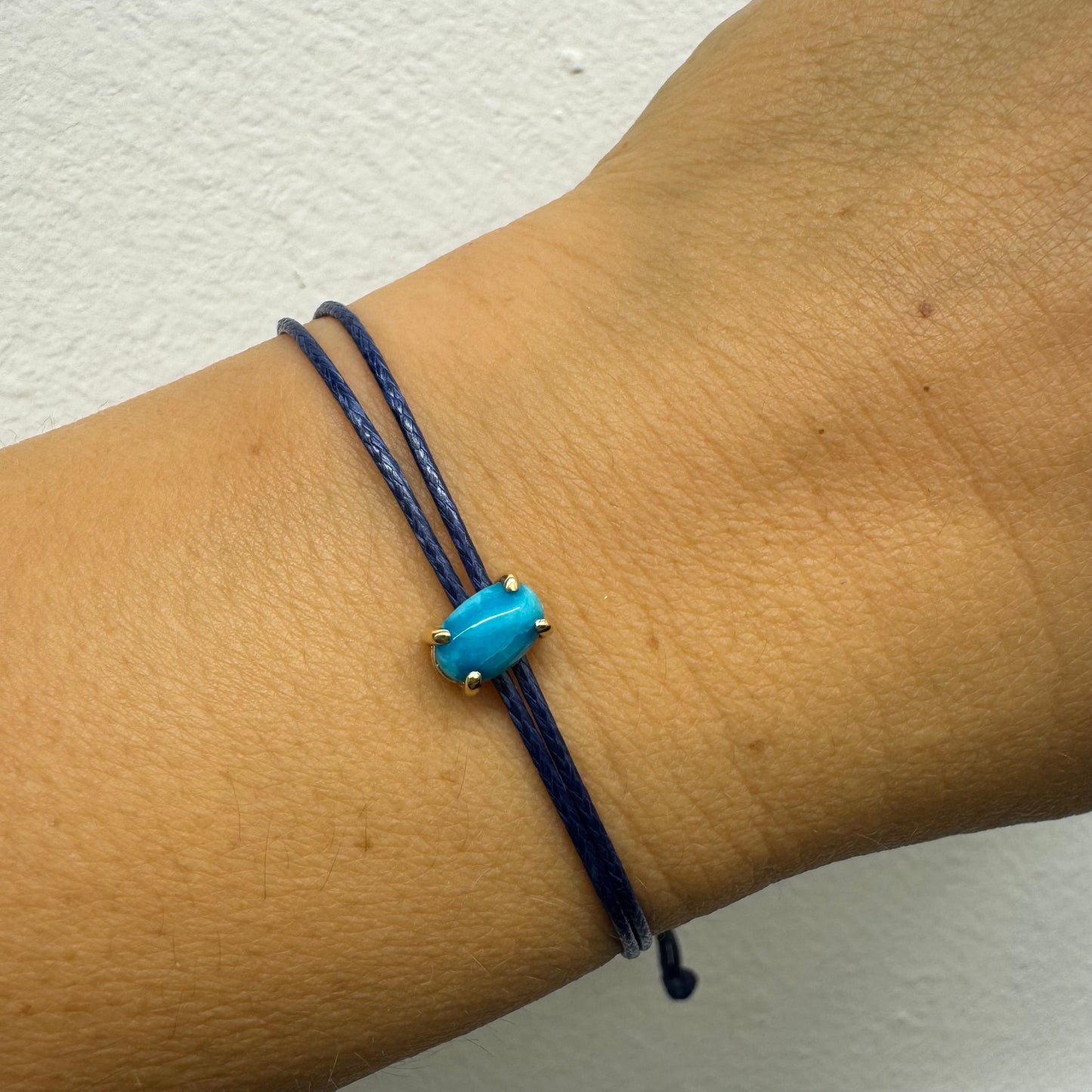 צמיד חוט כחול עדין עם אבן טורקיז טבעית בגוון כחול עמוק, משובצת במסגרת זהב.