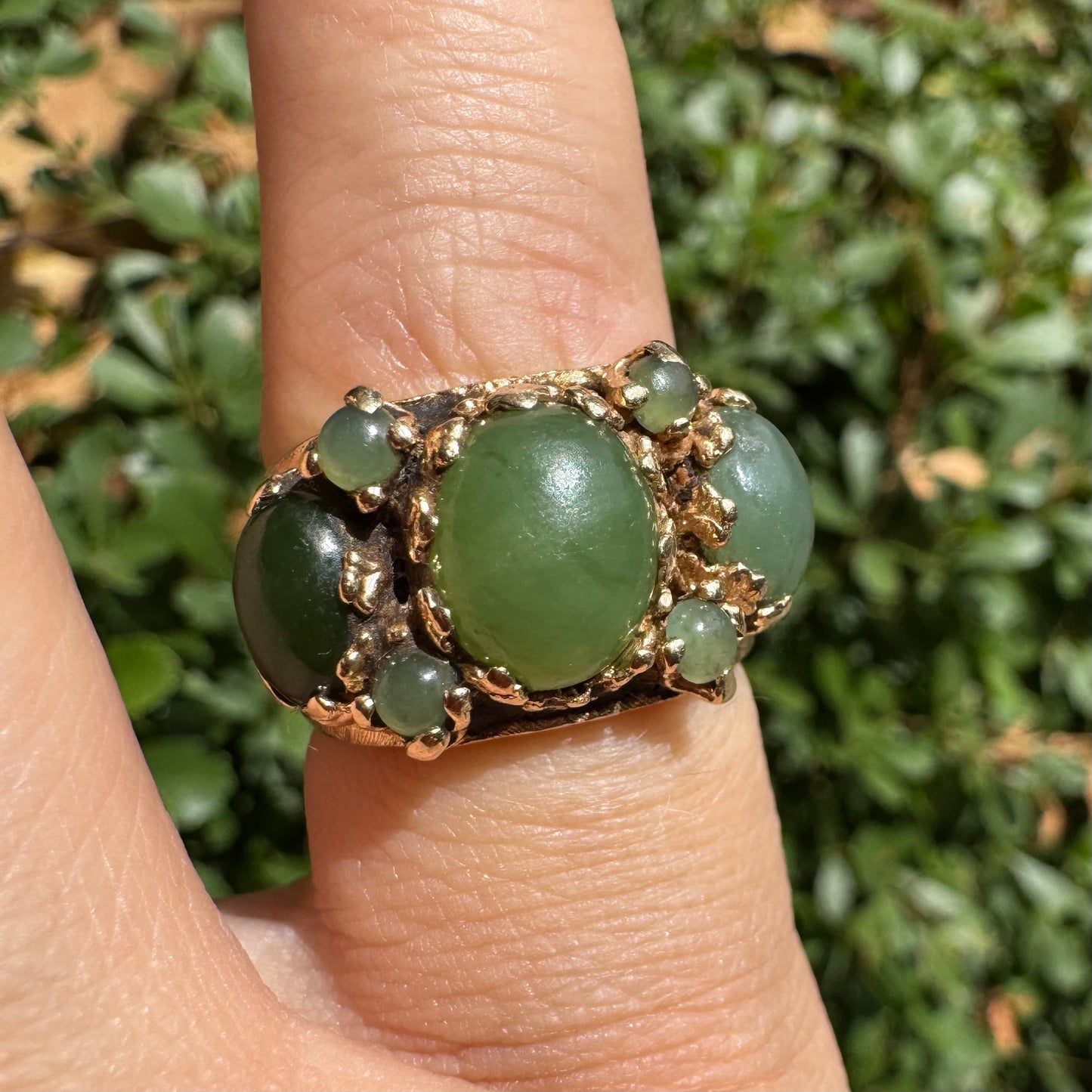 טבעת זהב צהוב 14 קראט משובצת באבני ג’ייד ירוקות בעיצוב בולט ותלת-ממדי.