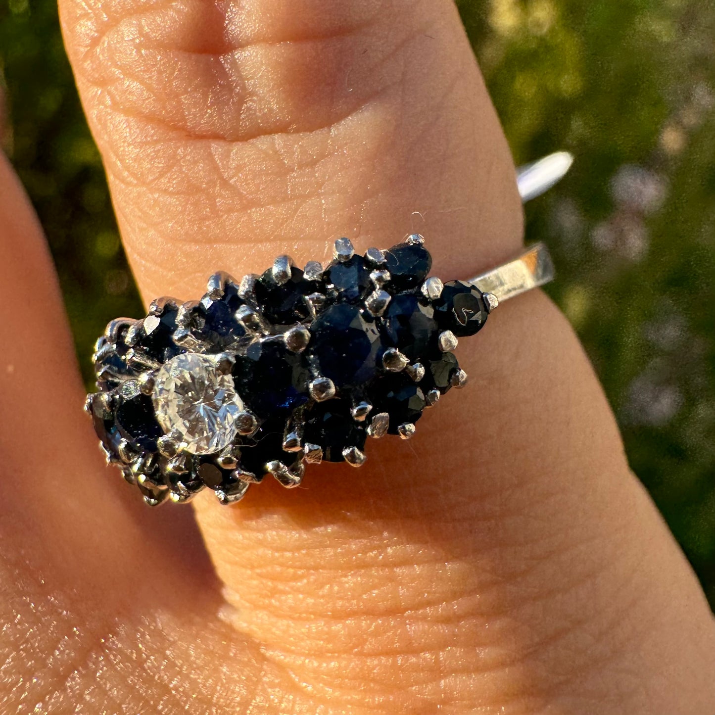 18K gold ring set with a brilliant-cut central Diamond, surrounded by a striking cluster of deep blue Sapphires.