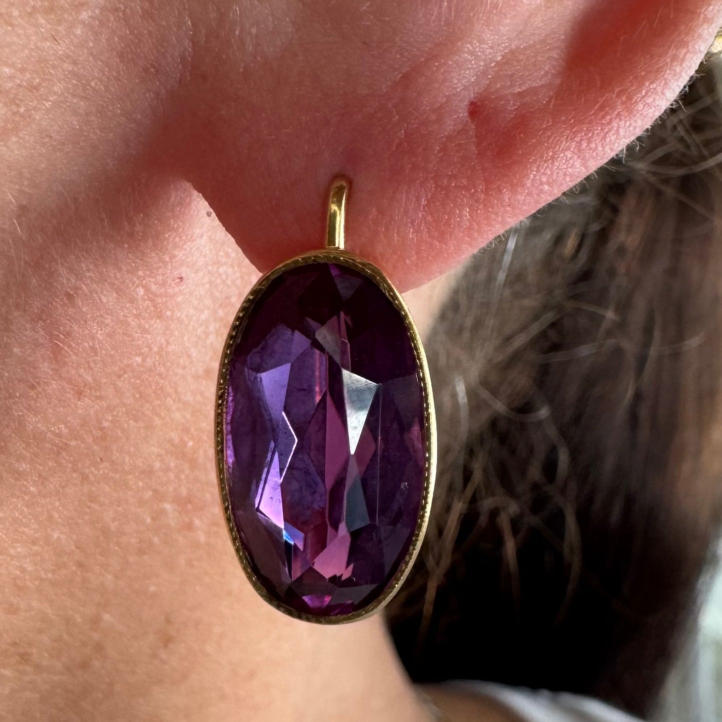 עגילי זהב צהוב 18 קראט, תלויים קצרים, משובצים באבני אמטיסט סגולות בחיתוך אובלי עמוק.