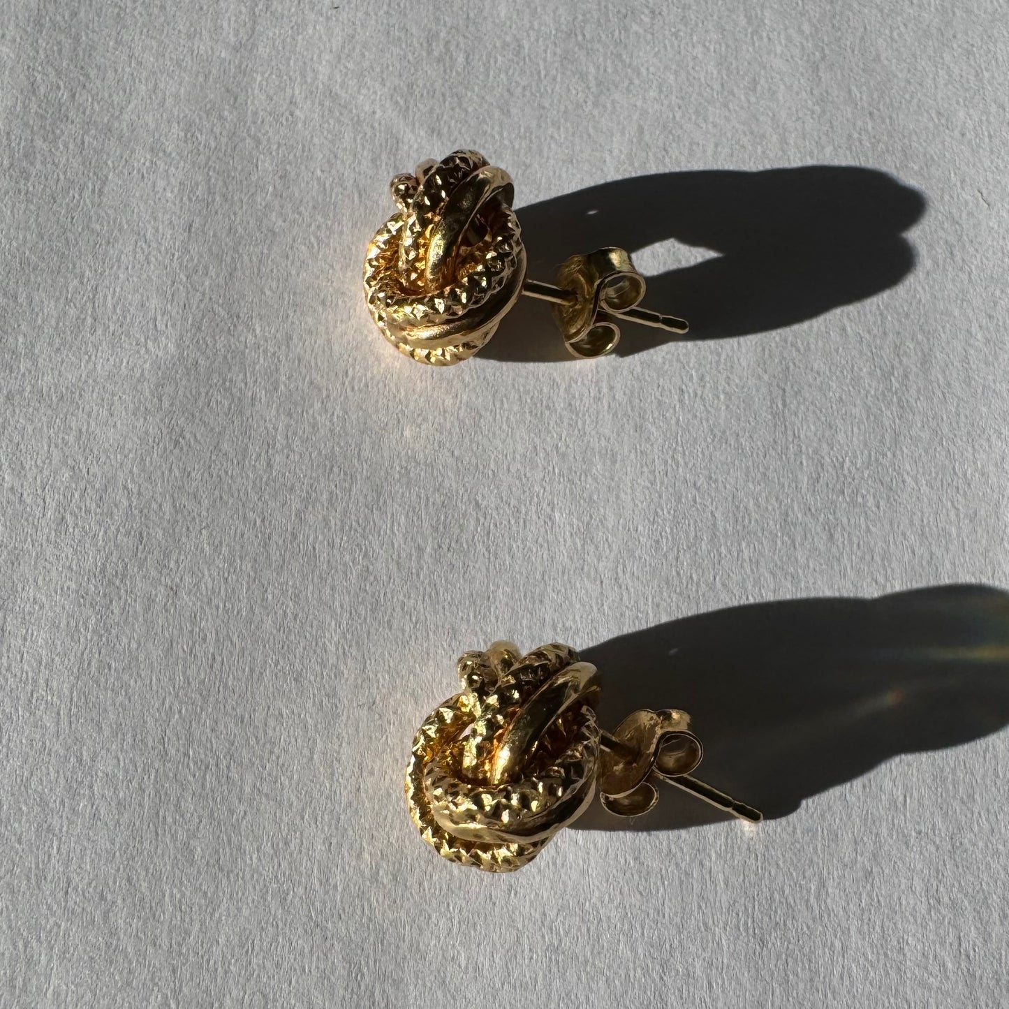 עגילי זהב צהוב 18 קראט בעיצוב קשר פיסולי, עם טקסטורה עשירה המדגישה את עומק וצורת הזהב.