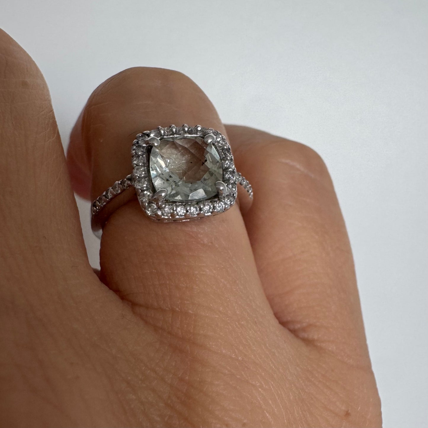 טבעת זהב לבן 14 קראט משובצת באבן אקוומרין בגוון תכלת ומוקפת במסגרת כפולה של יהלומים עגולים מנצנצים.