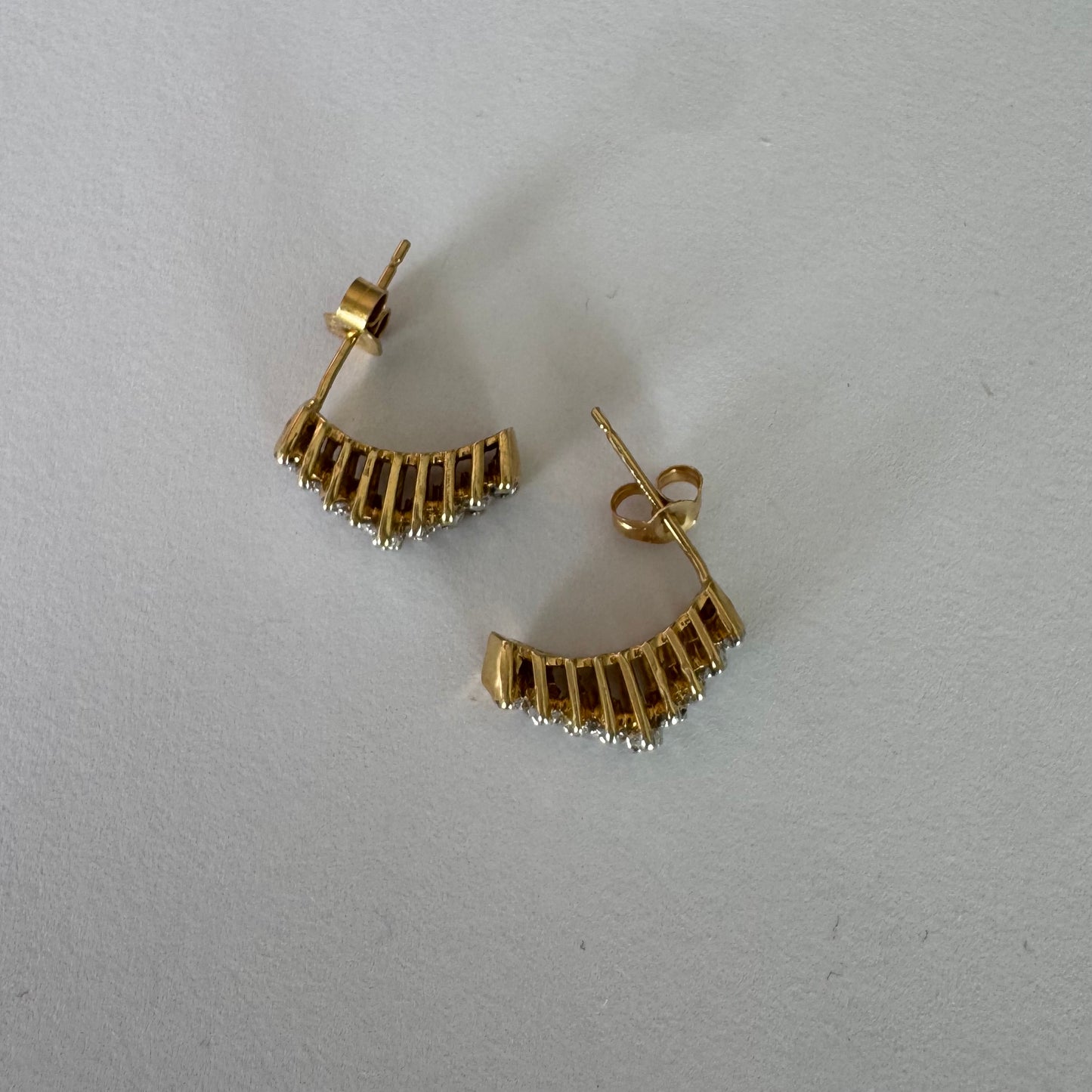 עגילי זהב צהוב 14 קראט בעיצוב חצי חישוק, משובצים יהלומים מנצנצים בשיבוץ צפוף המעניק מראה עשיר ונוכח.