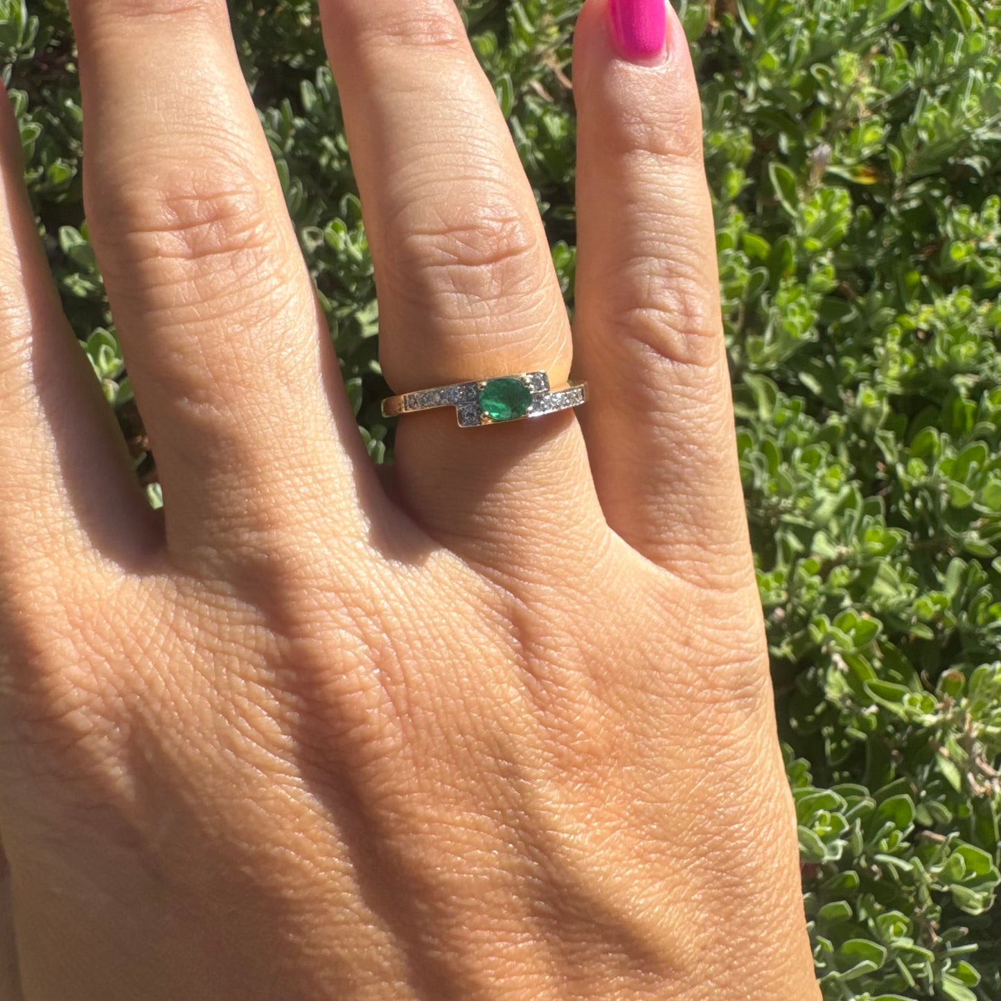 18K gold ring set with an oval green Emerald at the center, accented with sparkling Diamonds along the band.