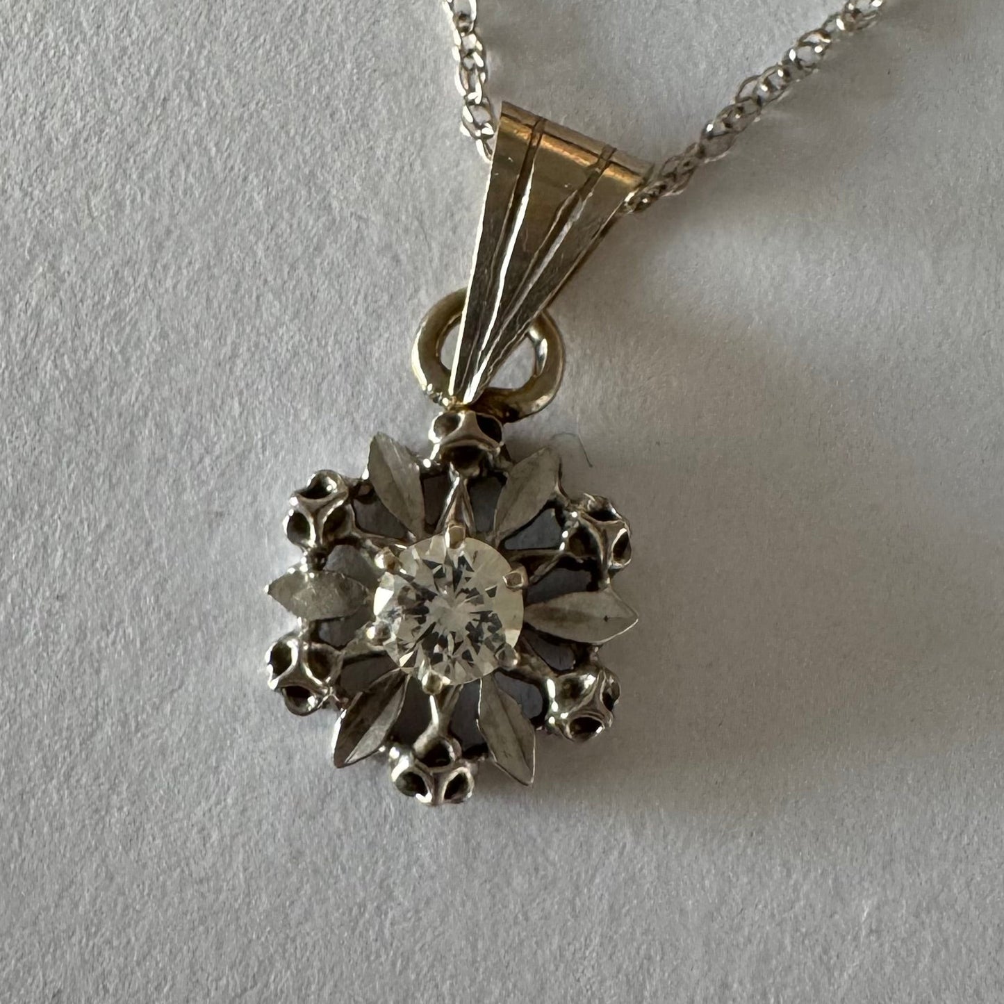 תליון זהב 14 קראט משובץ יהלום מרכזי בעיצוב פרח עדין ומלא נוכחות.