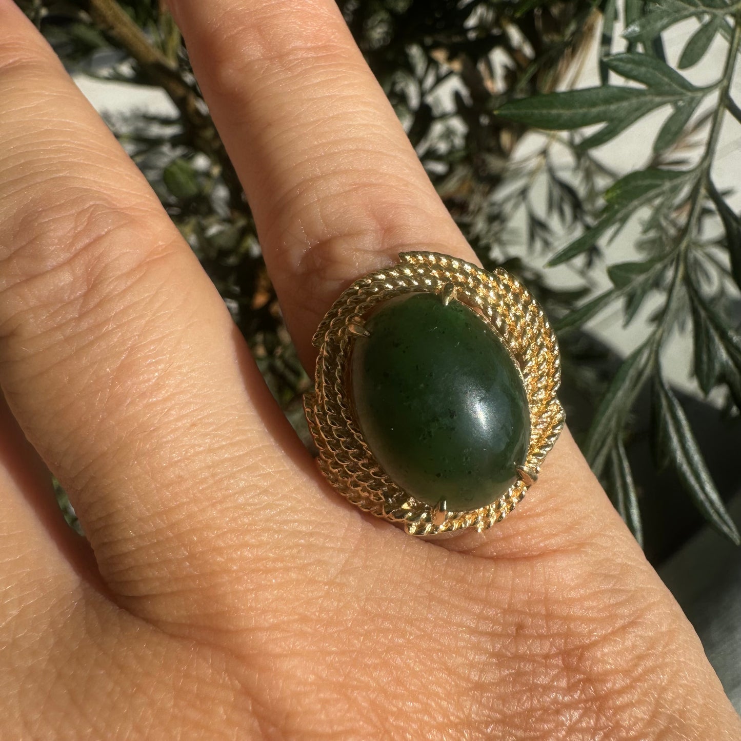 14K gold ring set with a deep green Jade set in a textured gold frame.