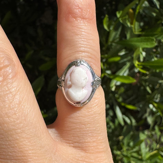 טבעת פלטינה משובצת בדמות פרופיל עדינה על רקע ורדרד-לבן, במסגרת מעוטרת בסגנון קלאסי.