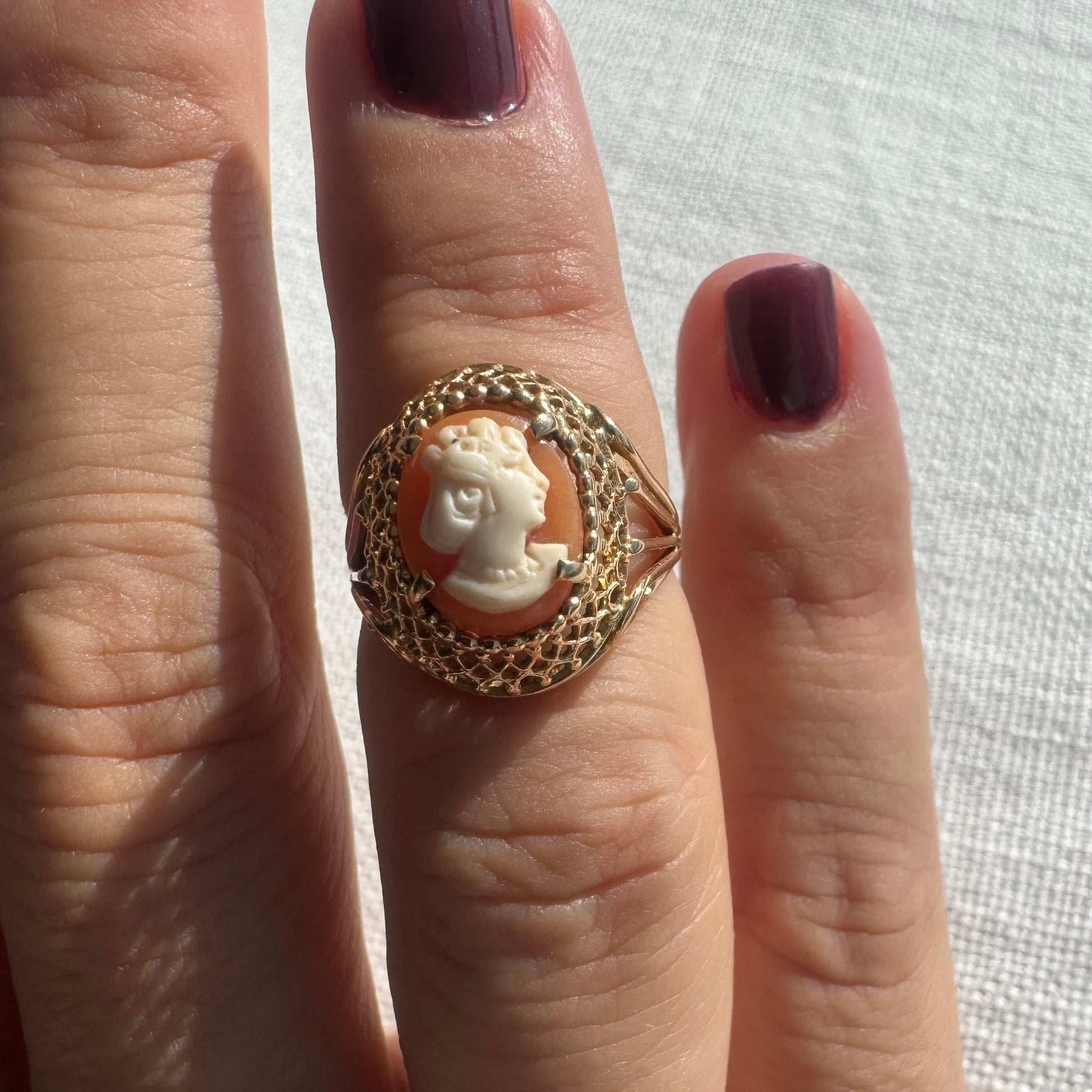 טבעת זהב צהוב 18 קראט, עם קמאו קלאסי בעבודת יד, המתאר פרופיל נשי עדין בגוון שנהב על רקע כתום-אלמוג.