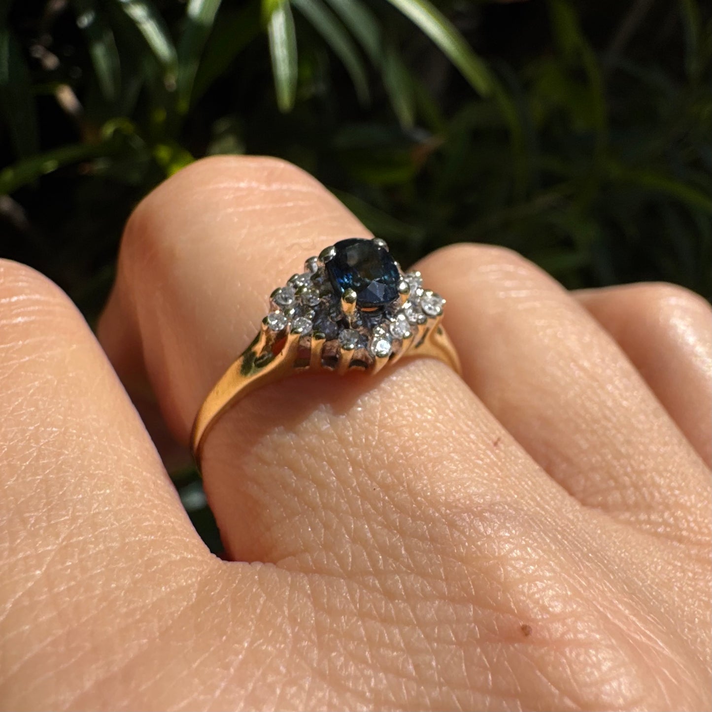 14K gold ring set with an oval blue Sapphire surrounded by sparkling Diamonds