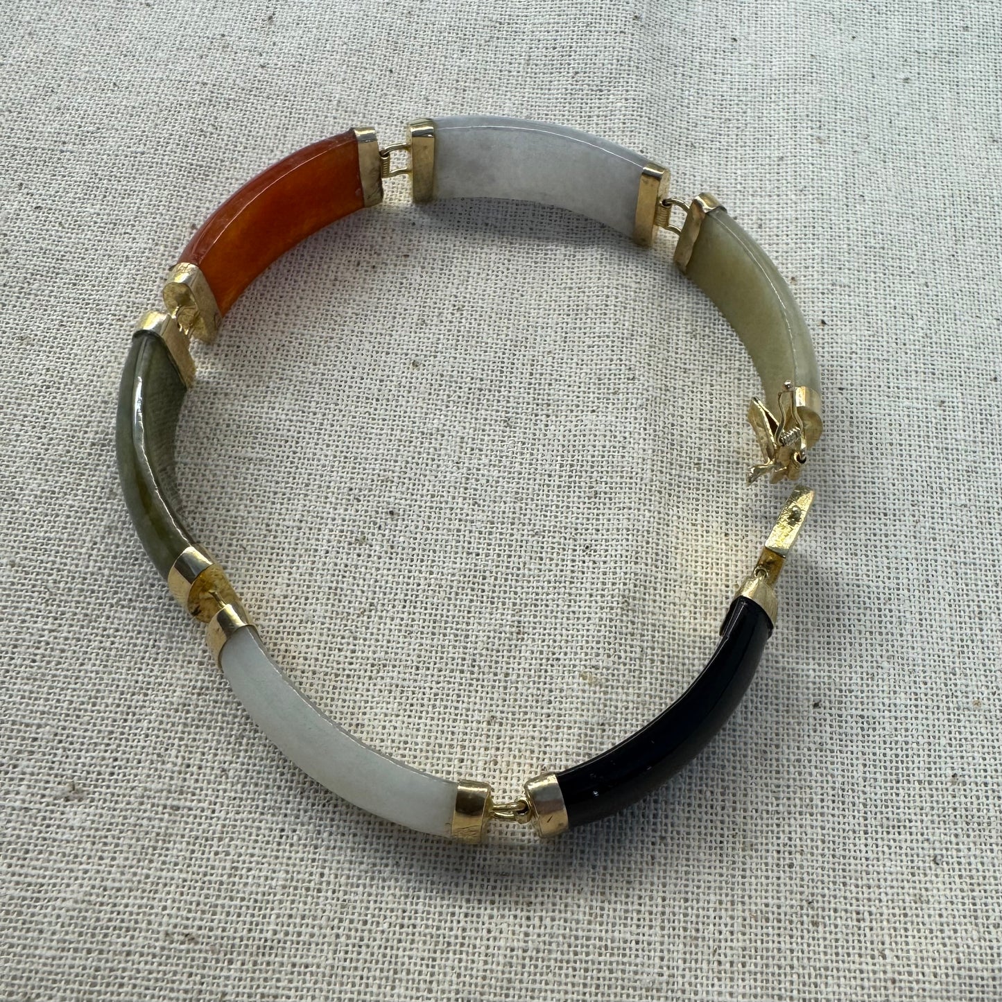 צמיד זהב צהוב 14 קראט עשוי מקטעי ג’ייד (jade) בשלושה גוונים – ירקרק, לבן ואדום – בשיבוץ זהב.