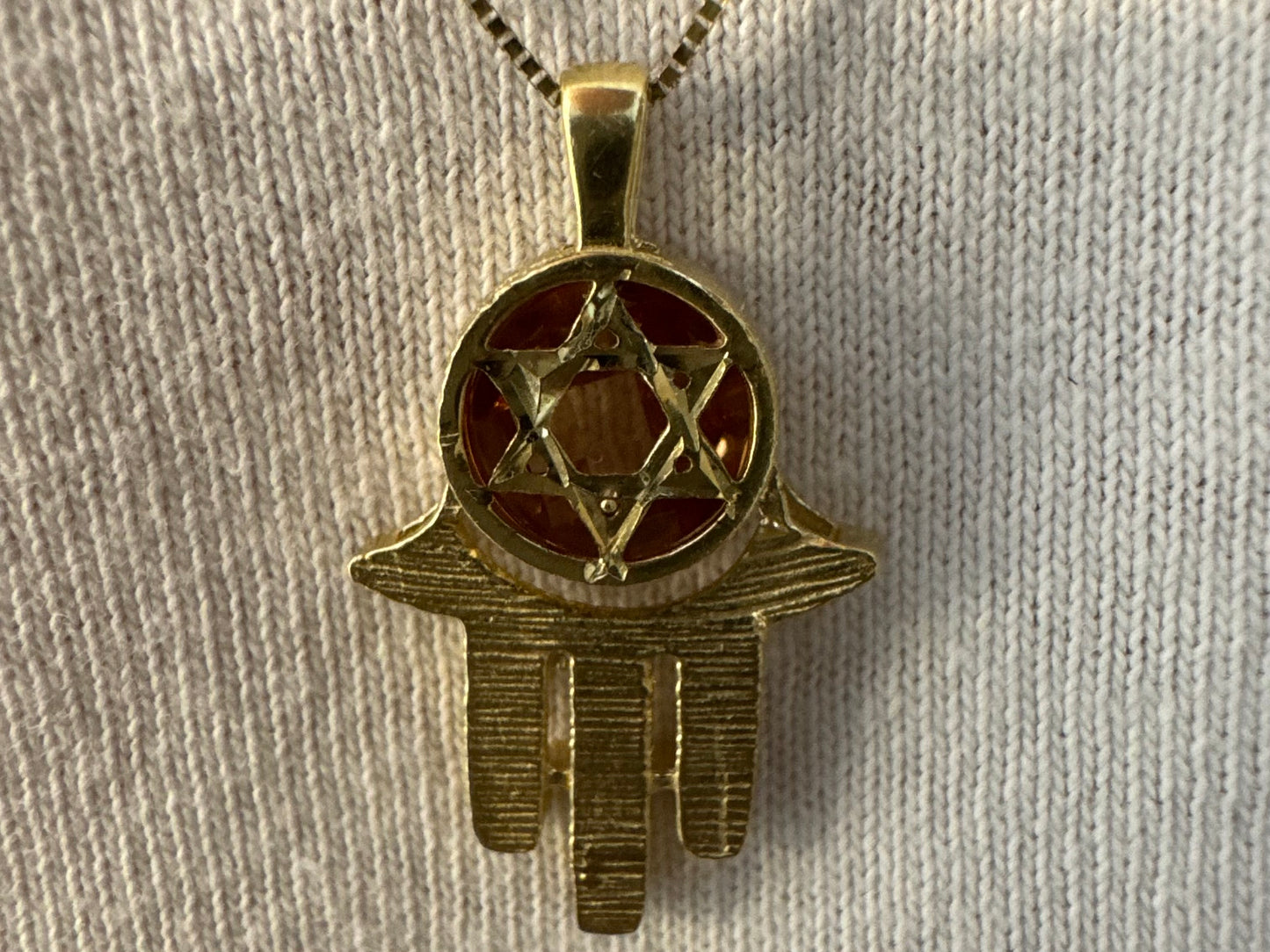 14K gold Hamsa pendant, featuring a deep orange gemstone framed by a Star of David.