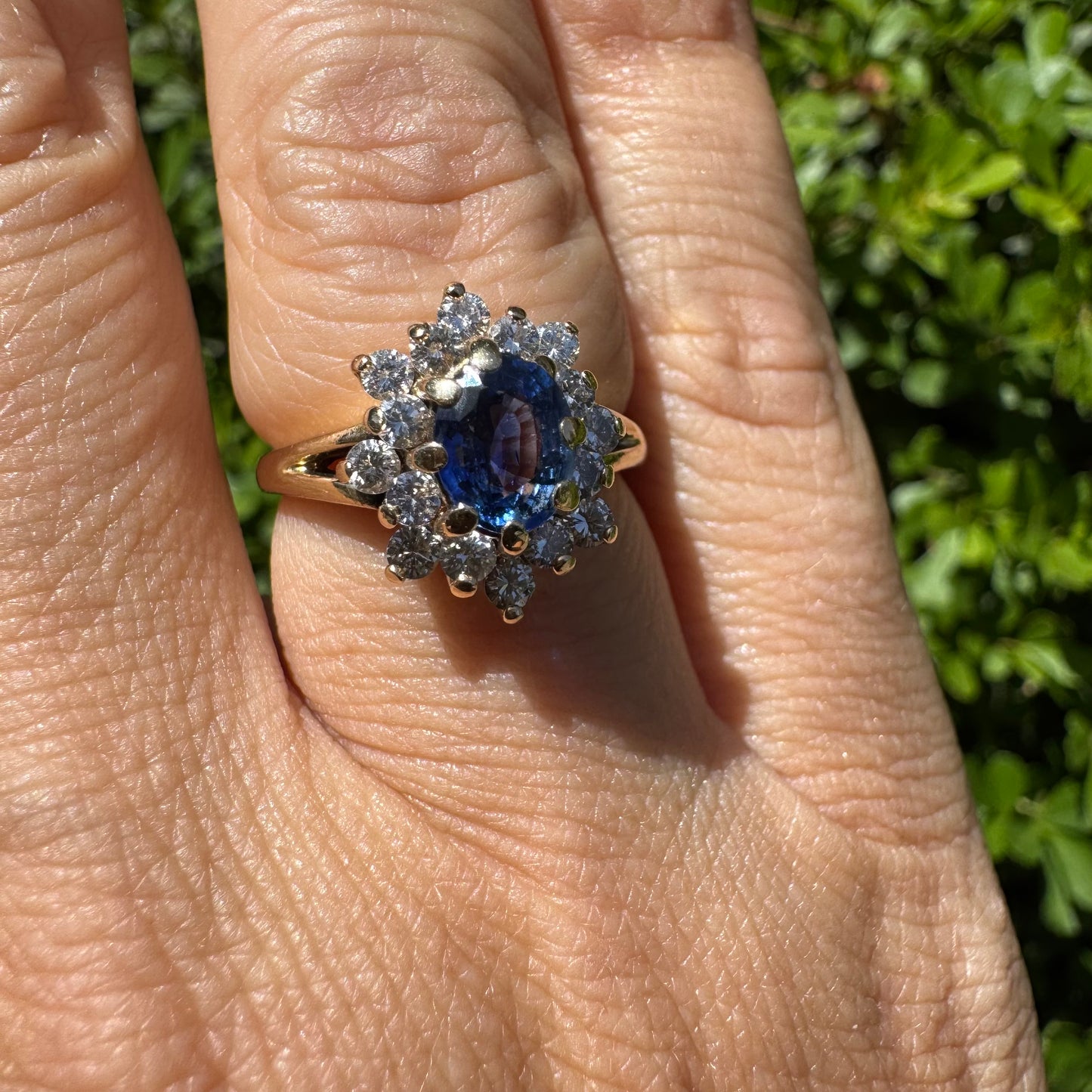 14K gold ring set with a vivid blue Sapphire surrounded by a sparkling halo of brilliant-cut Diamonds