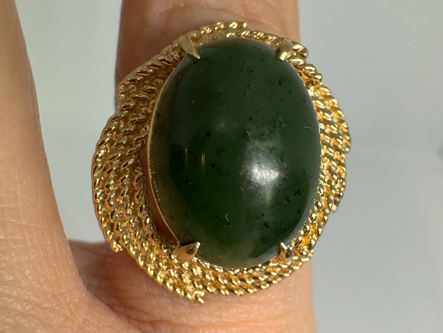14K gold ring set with a deep green Jade set in a textured gold frame.