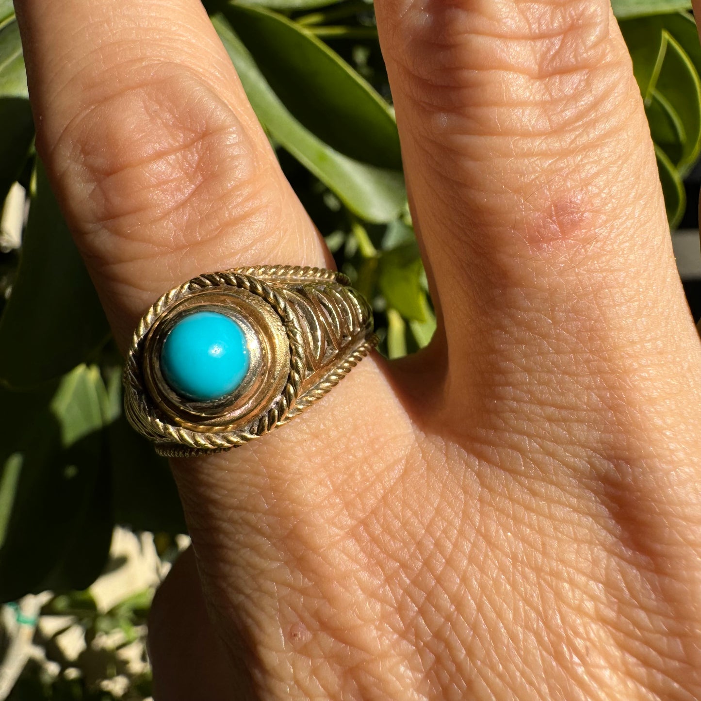 14K gold ring set with a round Turquoise stone at its center framed by a double rope-style bezel