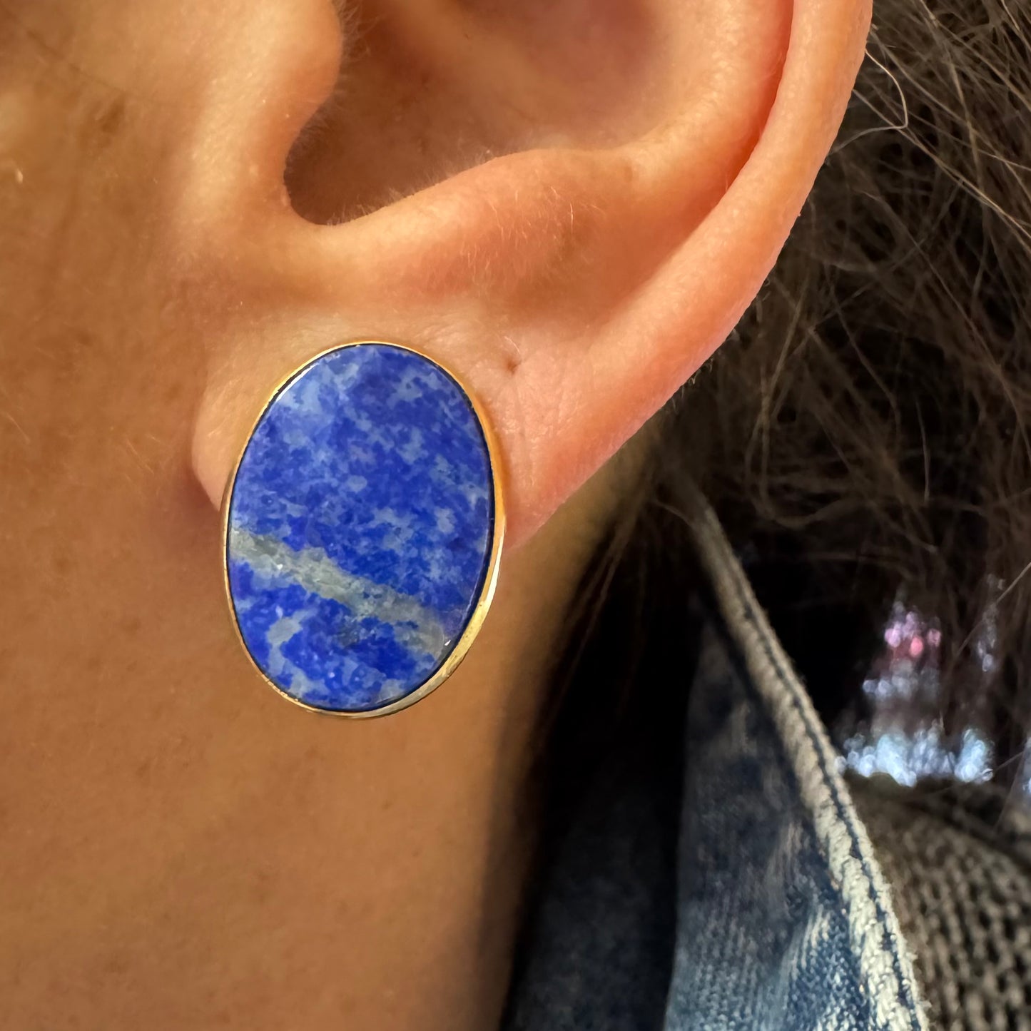 14K gold stud earrings set with polished oval Lapis Lazuli stones in a sleek gold bezel setting.