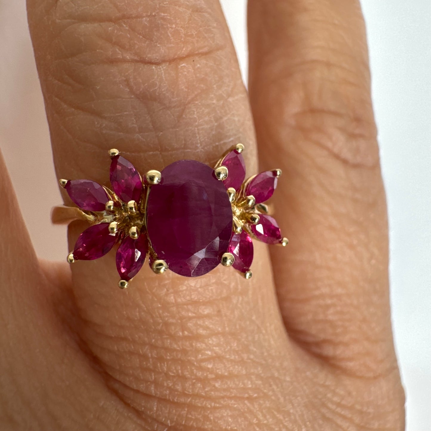 טבעת זהב צהוב 14 קראט משובצת רובי מרכזי גדול ולצידו רובי בחיתוך מרקיזה בעיצוב פרחוני עשיר.