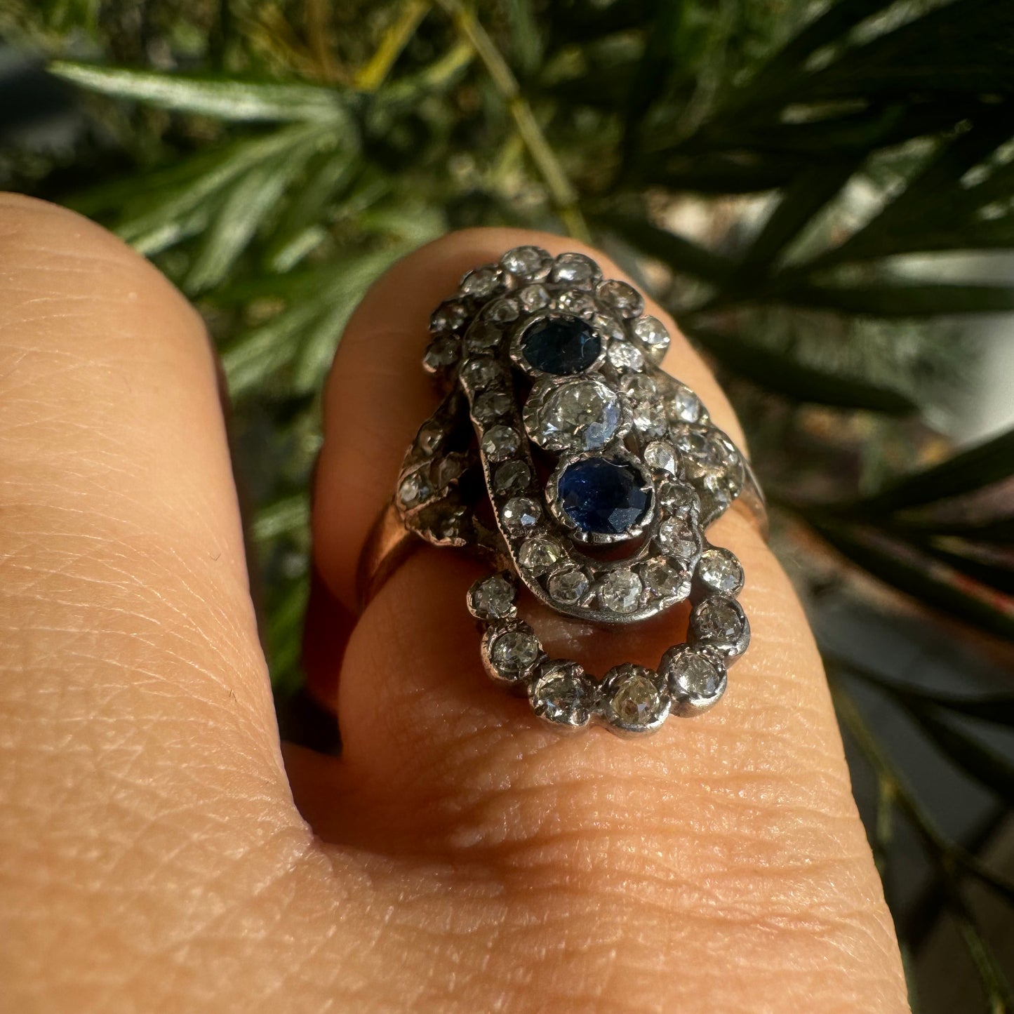 14K gold Antique featuring a stunning trio of gemstones - two deep blue Sapphires surrounding a brilliant old-cut Diamonds
