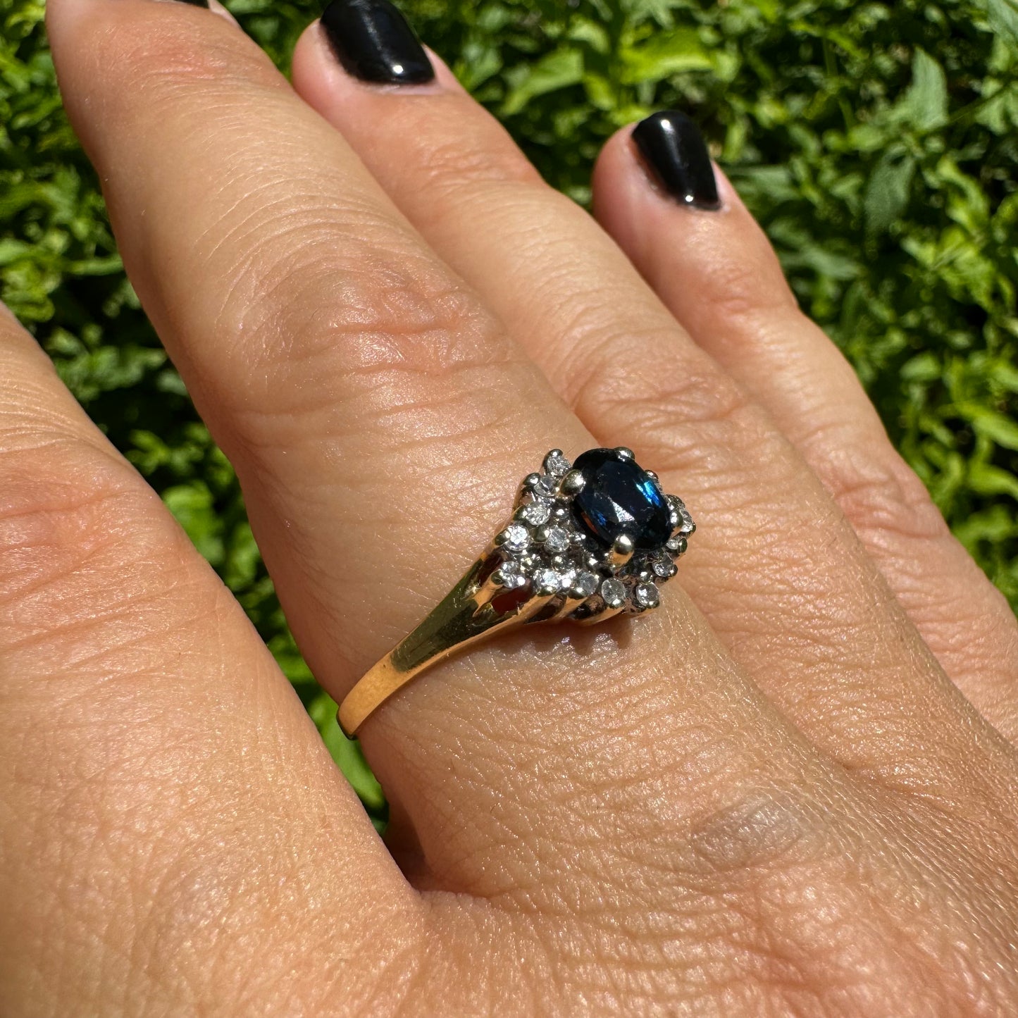 14K gold ring set with an oval blue Sapphire surrounded by sparkling Diamonds