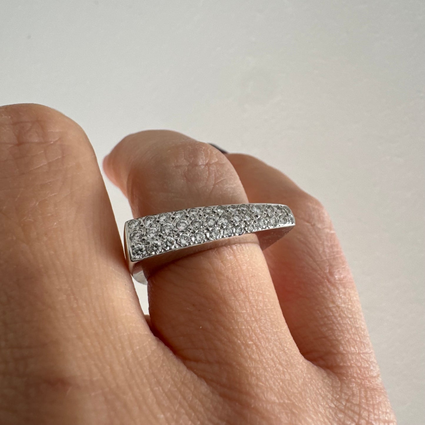 טבעת זהב לבן 18 קראט בגימור לבן, משובצת יהלומים בשיבוץ פאבה צפוף לכל רוחבה.