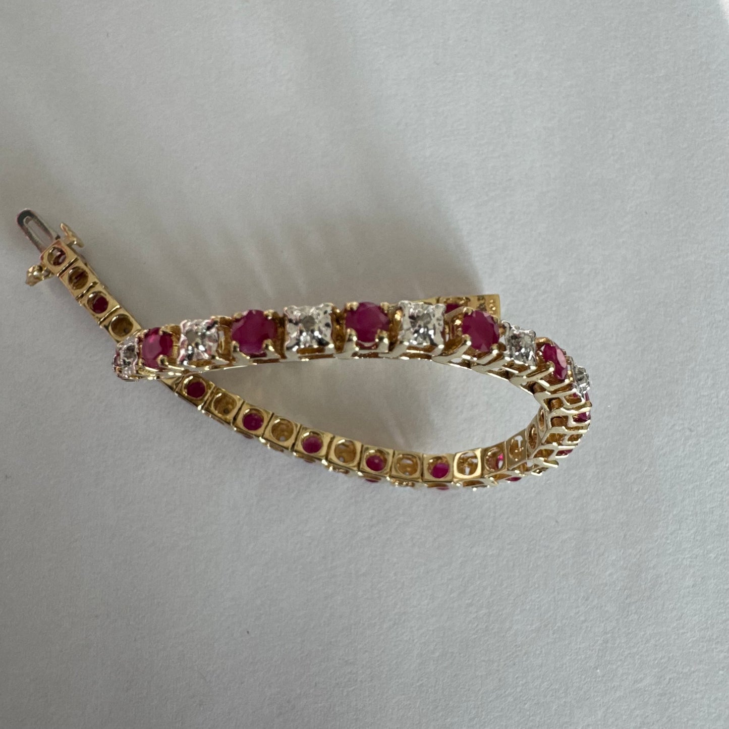צמיד זהב צהוב 10 קראט משובץ אבני רובי בגוון אדום עמוק וביניהן יהלומים לבנים מנצנצים.