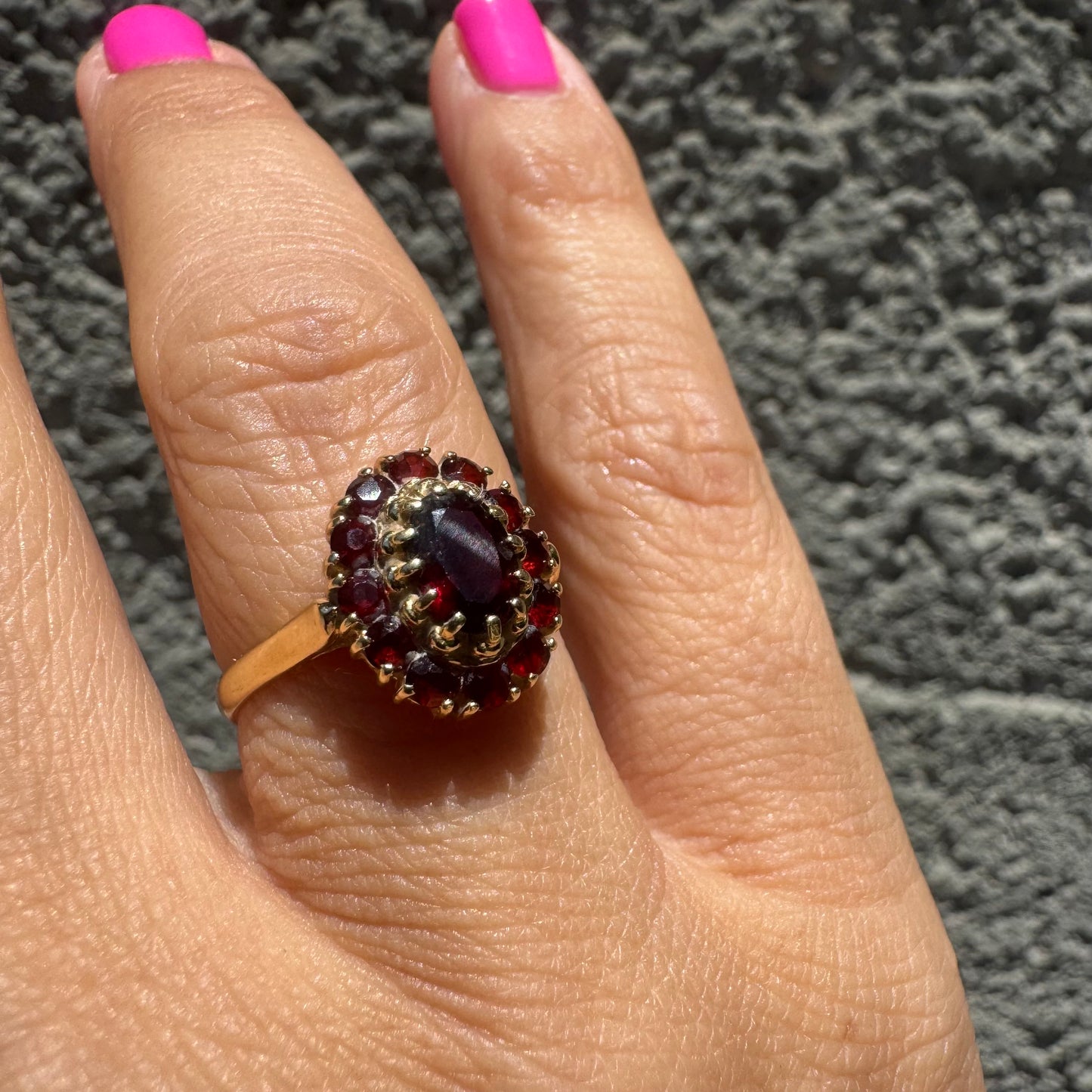 18K gold ring set with an oval garnet center stone, surrounded by smaller garnets