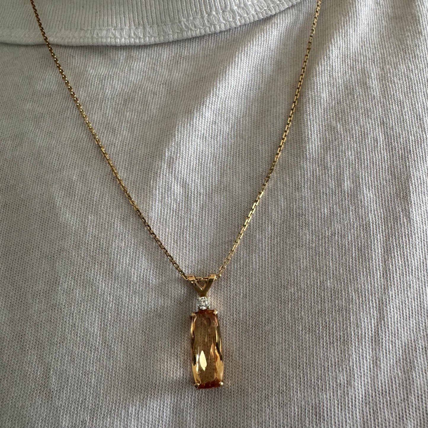 שרשרת זהב 14 קראט עם תליון זהב 14 קראט משובץ אבן קוורץ מלבנית בגוון שמפניה חמים, ומעליה יהלום נוצץ להדגשה עדינה של הברק.