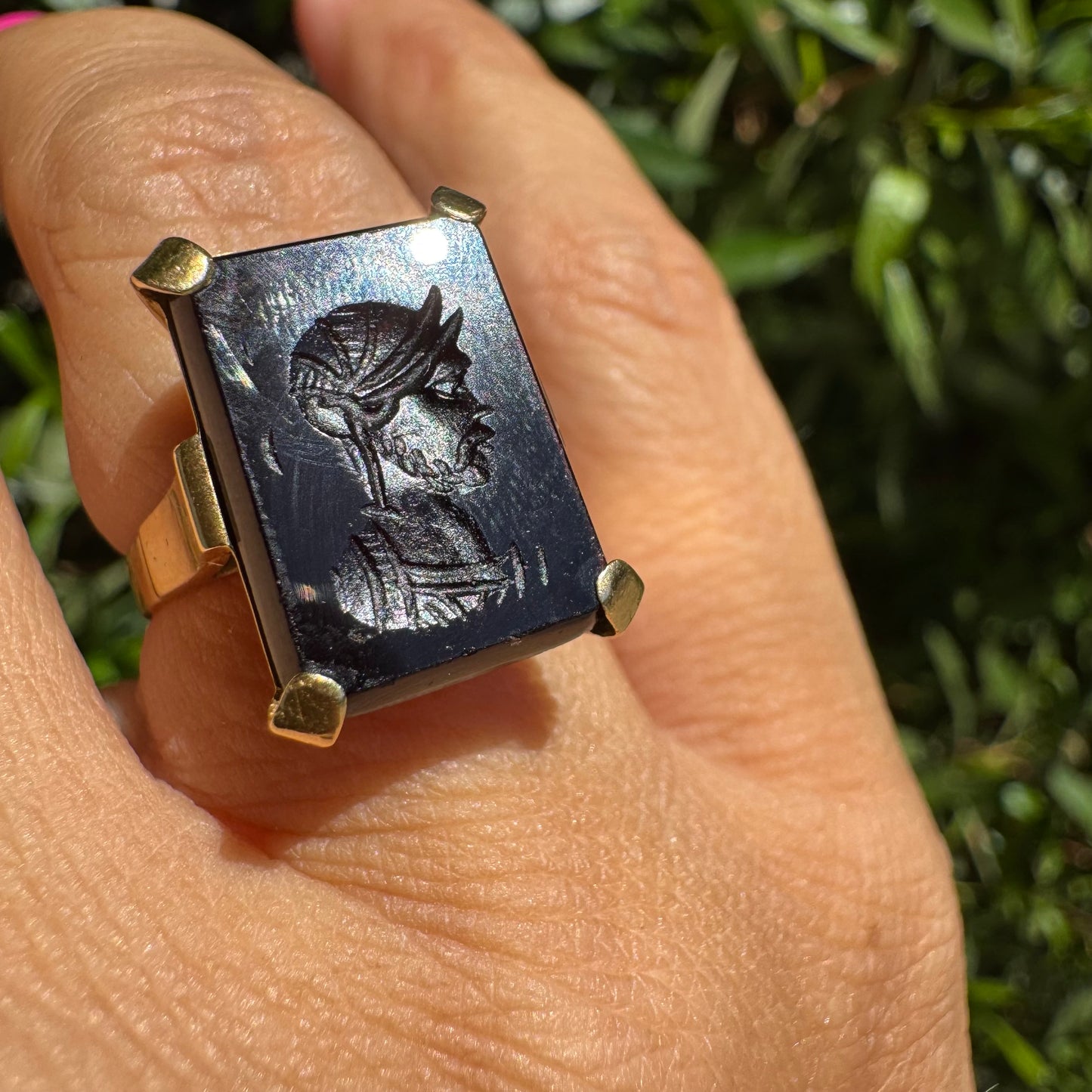18K gold ring set with a carved dark stone featuring a classical warrior profile.