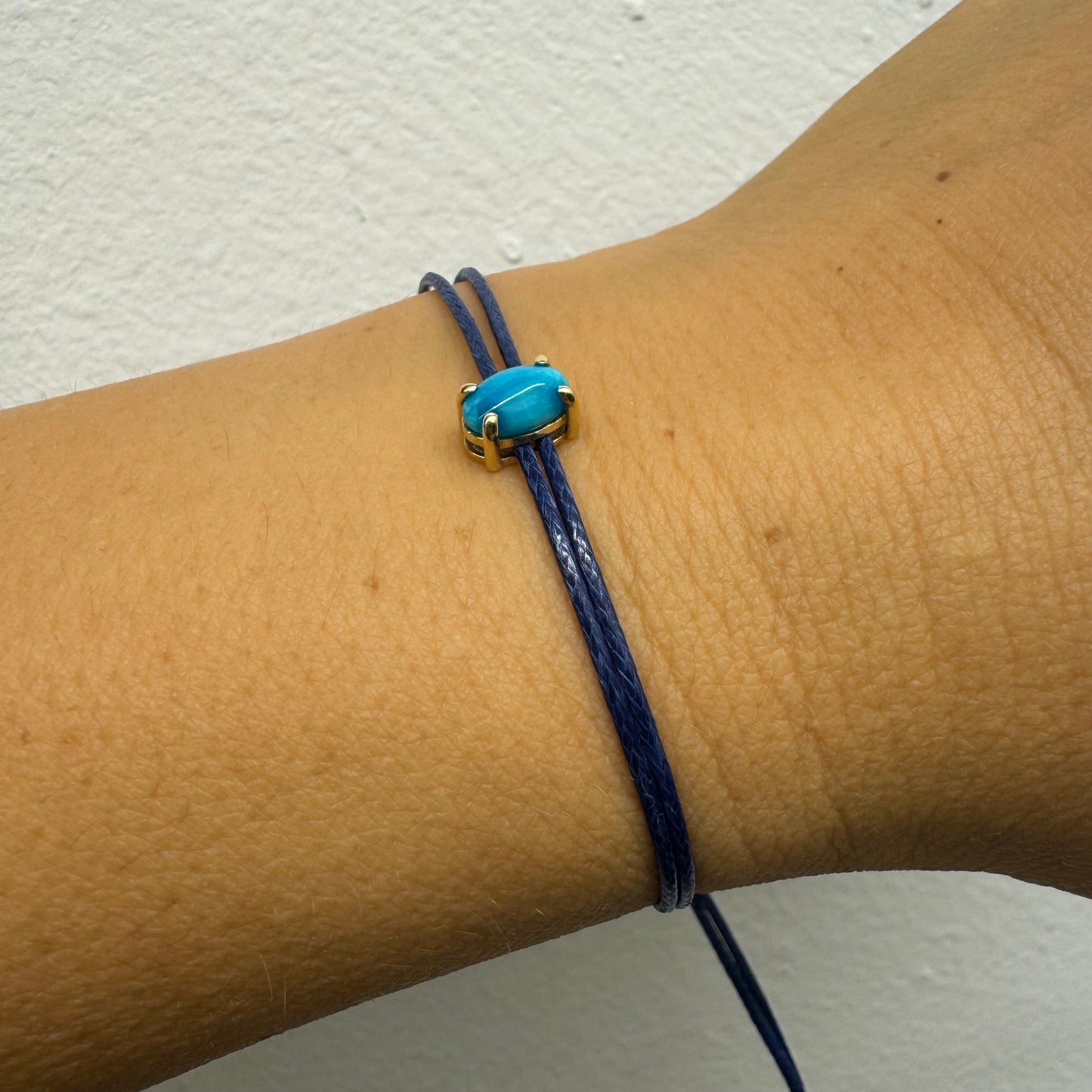 צמיד חוט כחול עדין עם אבן טורקיז טבעית בגוון כחול עמוק, משובצת במסגרת זהב.