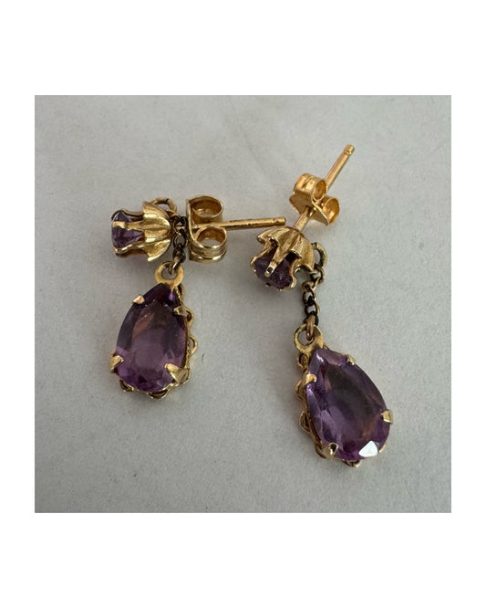 עגילים זהב צהוב 14 קראט משובצים אבני אמטיסט בגוון סגול עמוק בחיתוך טיפה, בשילוב אבן עליונה תואמת ועיטור שרשרת עדינה המחברת ביניהן.