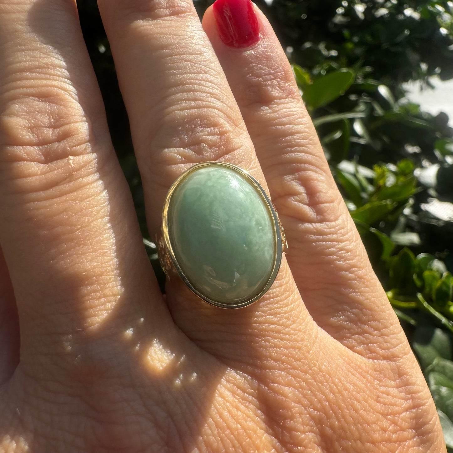 14K gold ring featuring a large oval light green Jade with a smooth polished finish, set in a classic bezel setting.