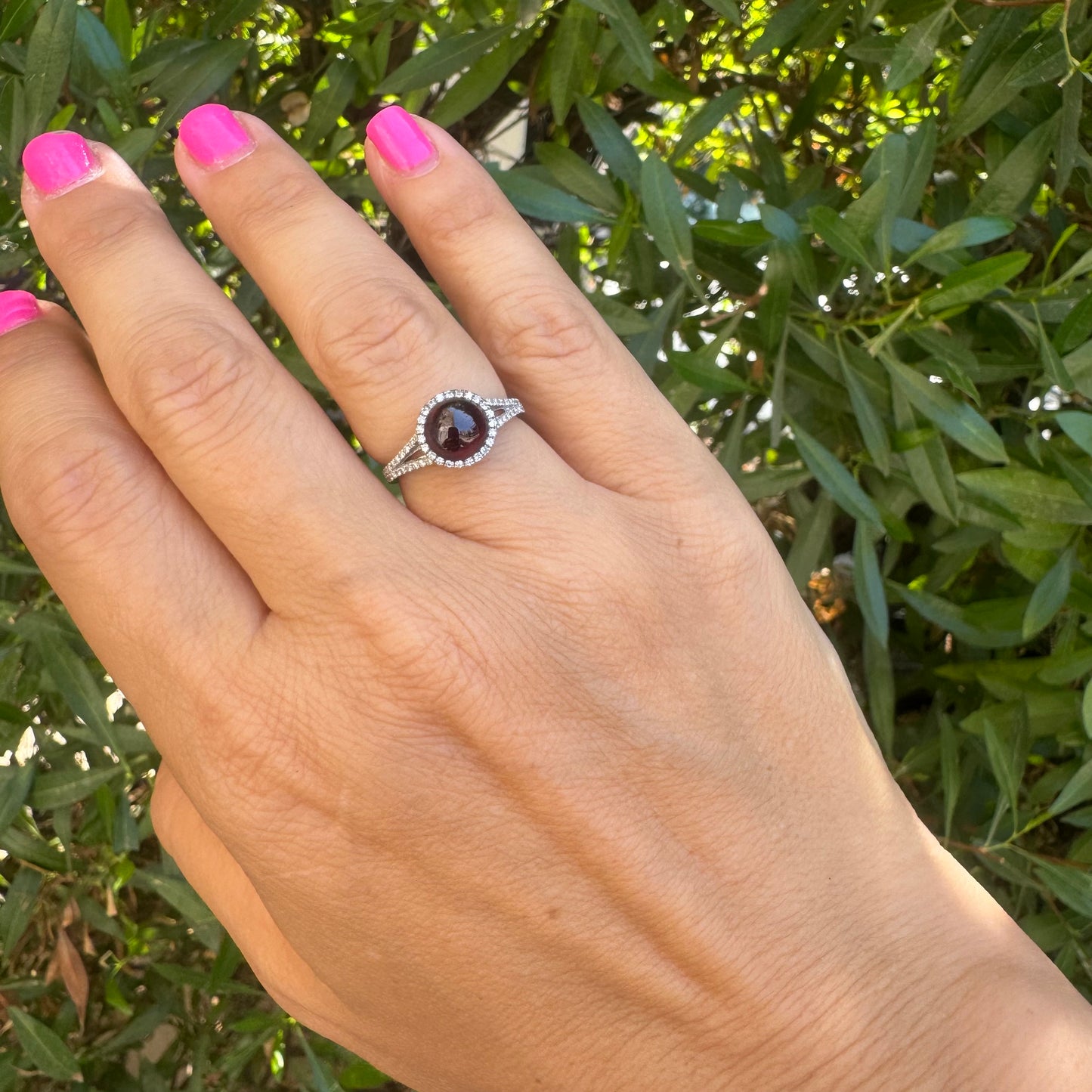 14K gold ring set with a deep red cabochon Garnet, surrounded by a halo of sparkling Diamonds
