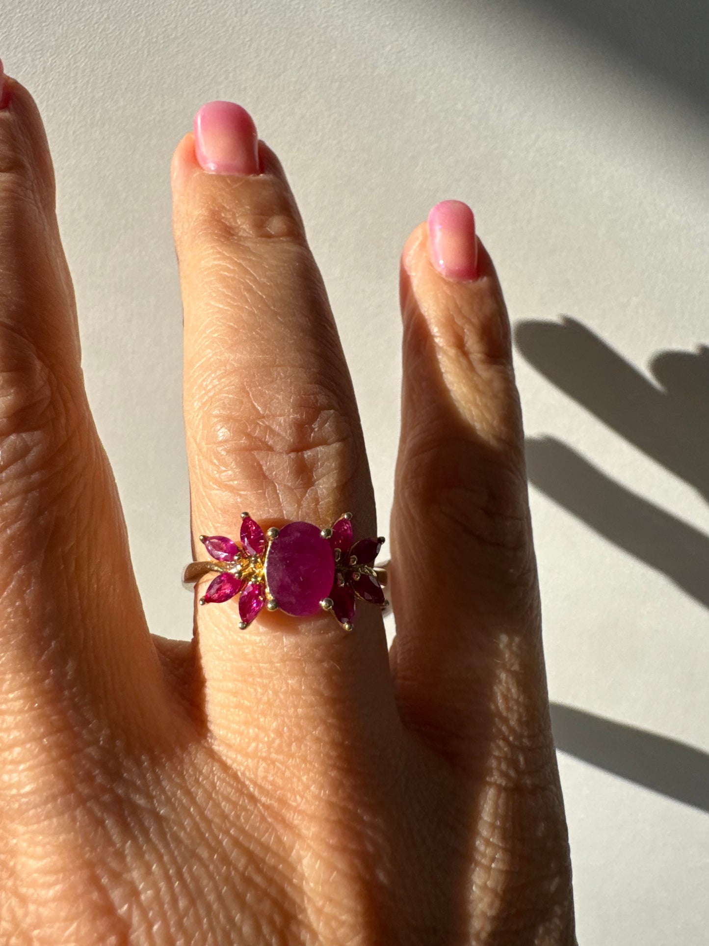 טבעת זהב צהוב 14 קראט משובצת רובי מרכזי גדול ולצידו רובי בחיתוך מרקיזה בעיצוב פרחוני עשיר.