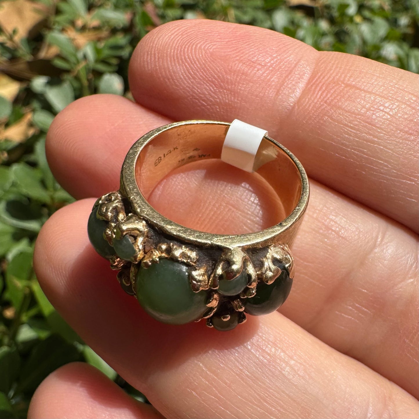 14K gold ring set with a central oval green Jade cabochon, framed by additional Jade stones in varying shades and sizes