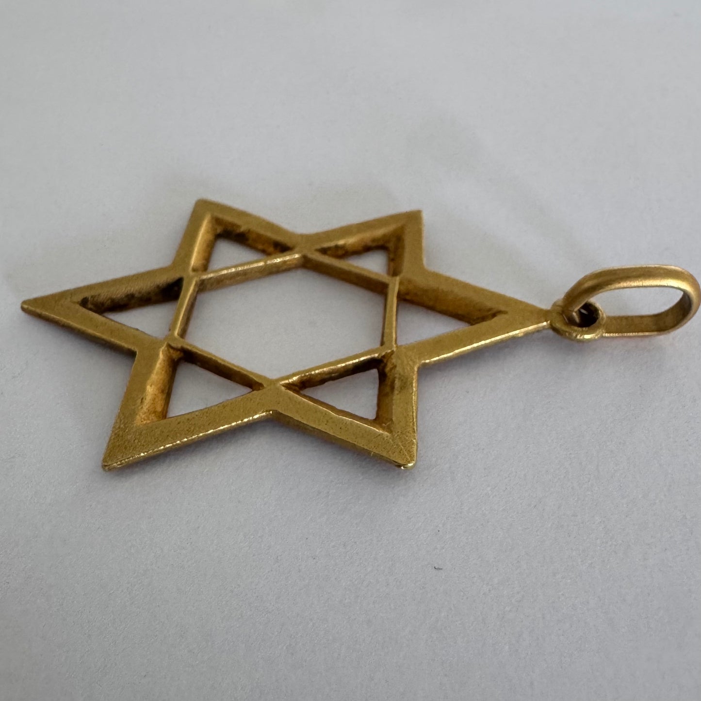 תליון מגן דוד מזהב צהוב 14 קראט בעיצוב פתוח, עם טקסטורה עדינה בשוליים המוסיפה עומק ואופי.