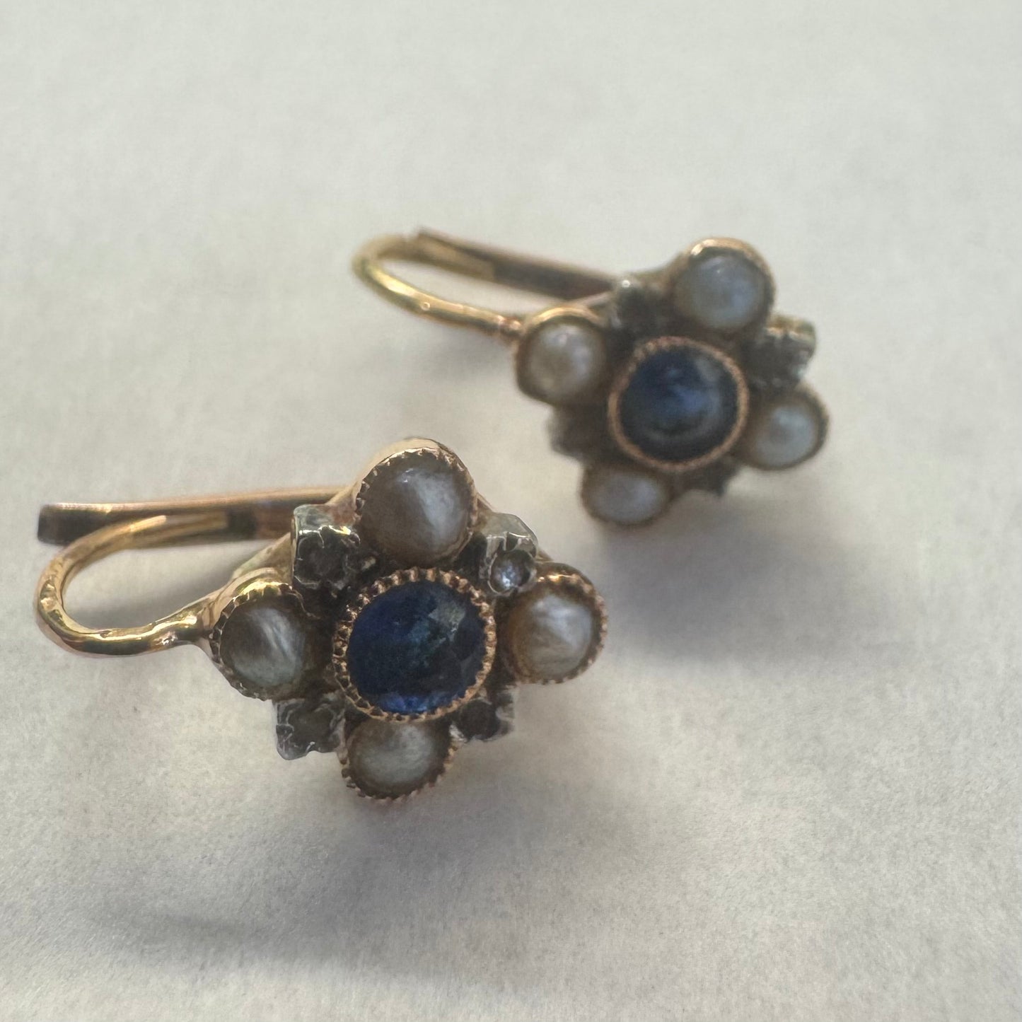 עגילי זהב 14 קראט משובצים אבן ספיר במרכז וסביבה משובצות פנינים קטנות בעיצוב פרחוני